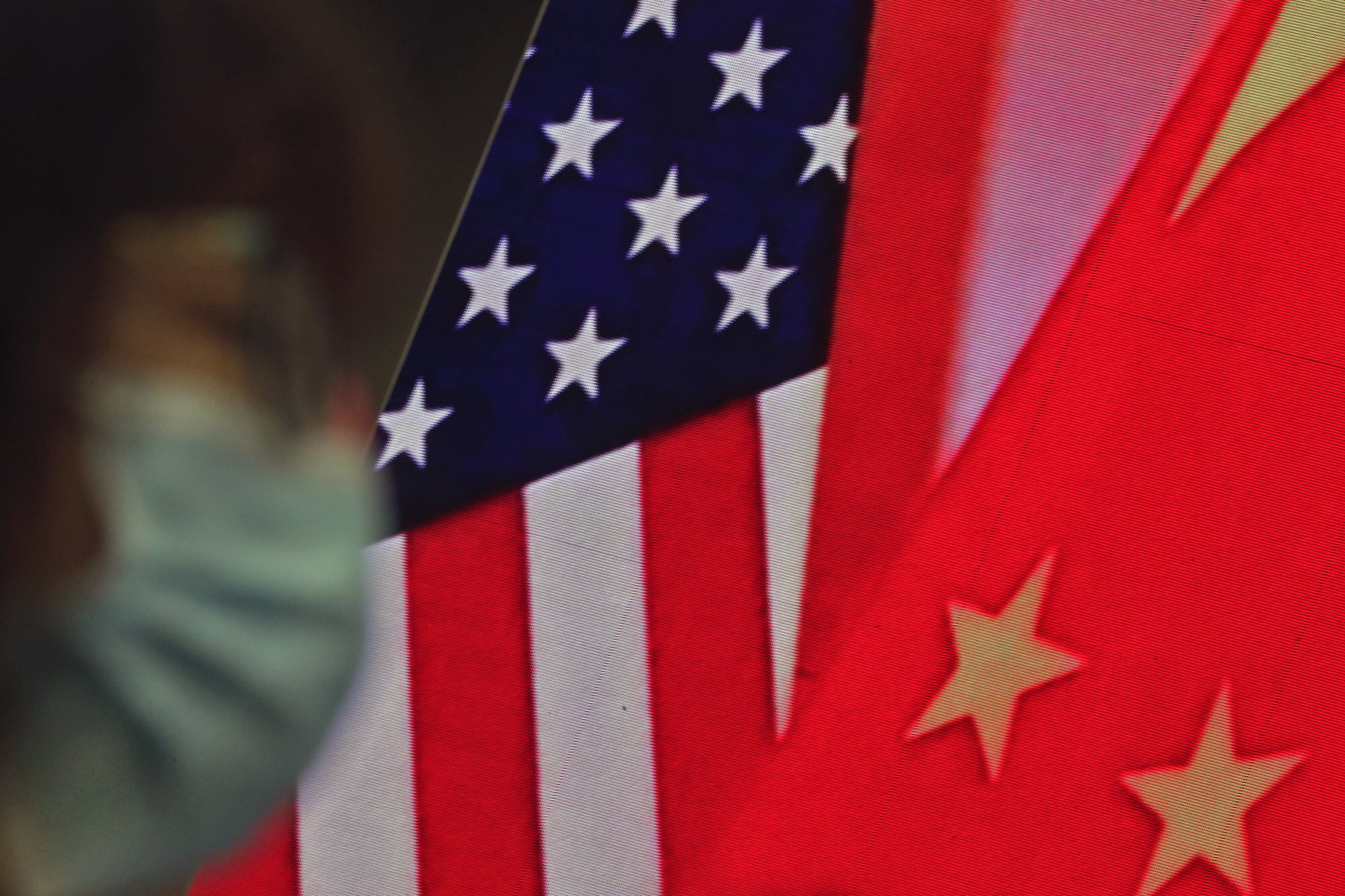 A woman wearing a face mask sits near a screen showing the Chinese and US flags as she listens to a speech by Chinese Foreign Minister Wang Yi at the Ministry of Foreign Affairs office in Beijing on February 22. A much-touted prism through which US-China relations are viewed today is the Thucydides trap. Photo: AP 