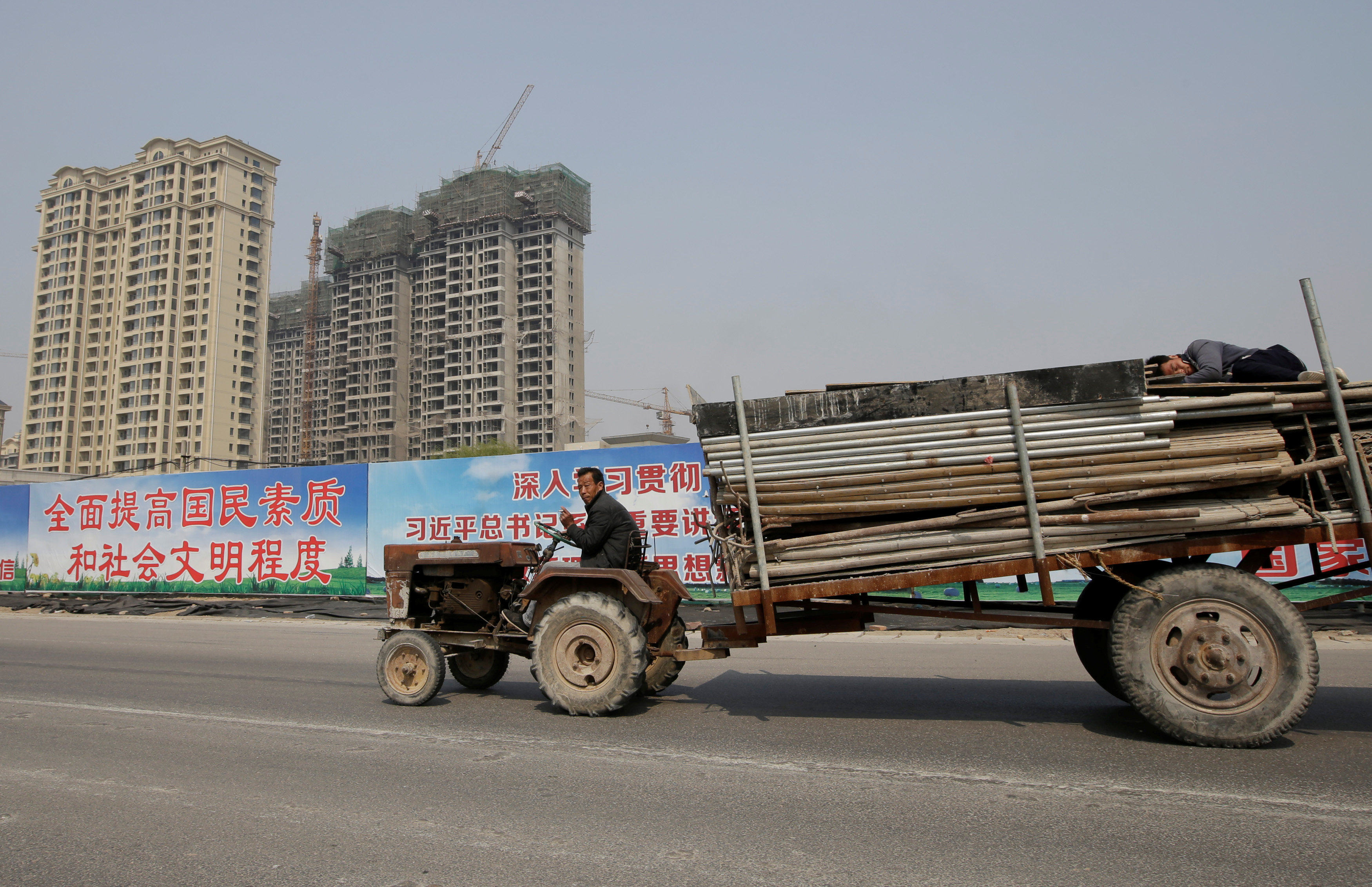 A man drives a tractor carrying building materials past a property under construction in Xiongxian county, Hebei province, China. Photo: Reuters