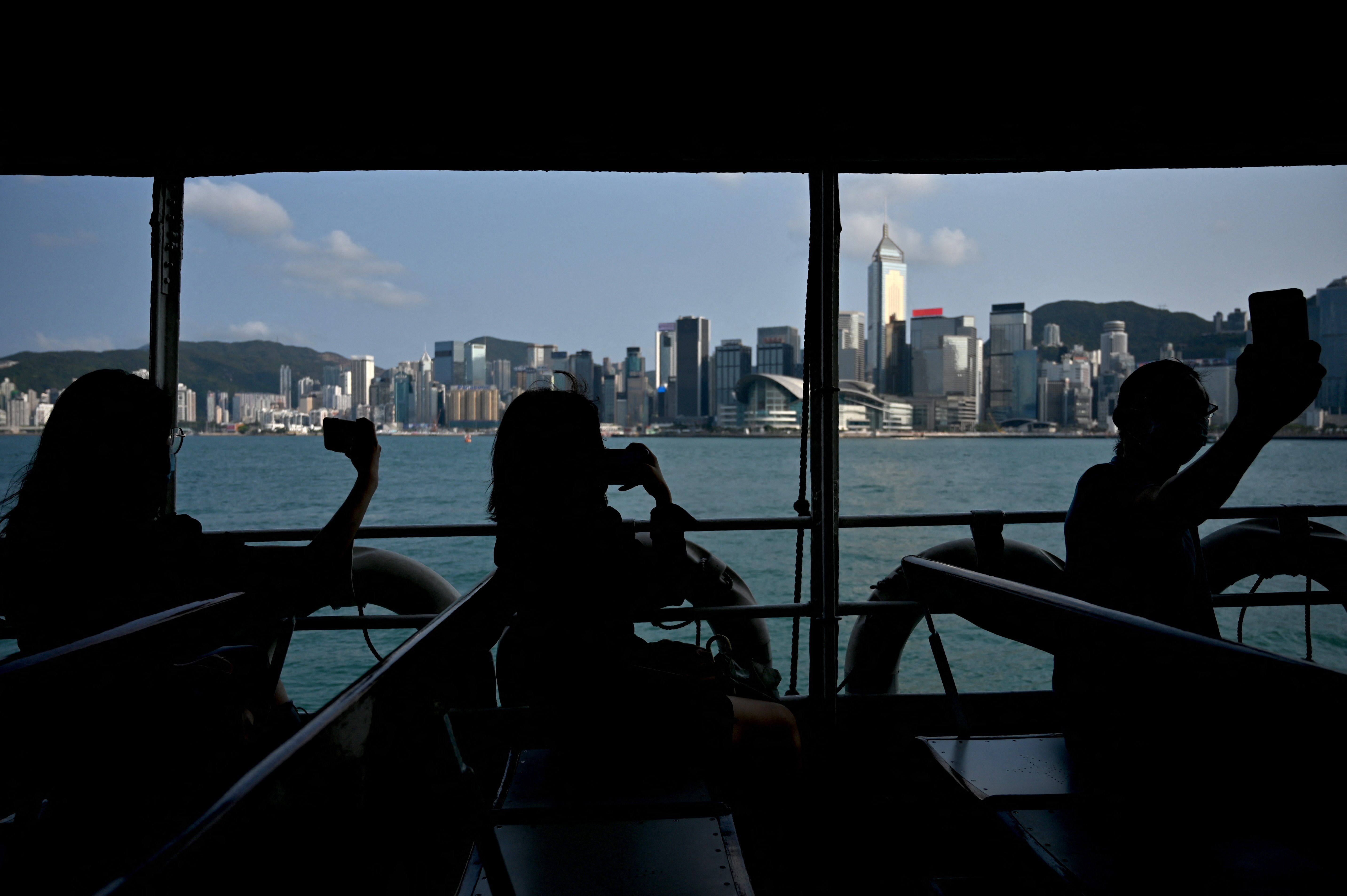 Buildings housing Hong Kong’s commercial and financial giants form the backdrop as passengers on the Star Ferry take photos of the city’s iconic Victoria Harbour on March 17. Photo: AFP 