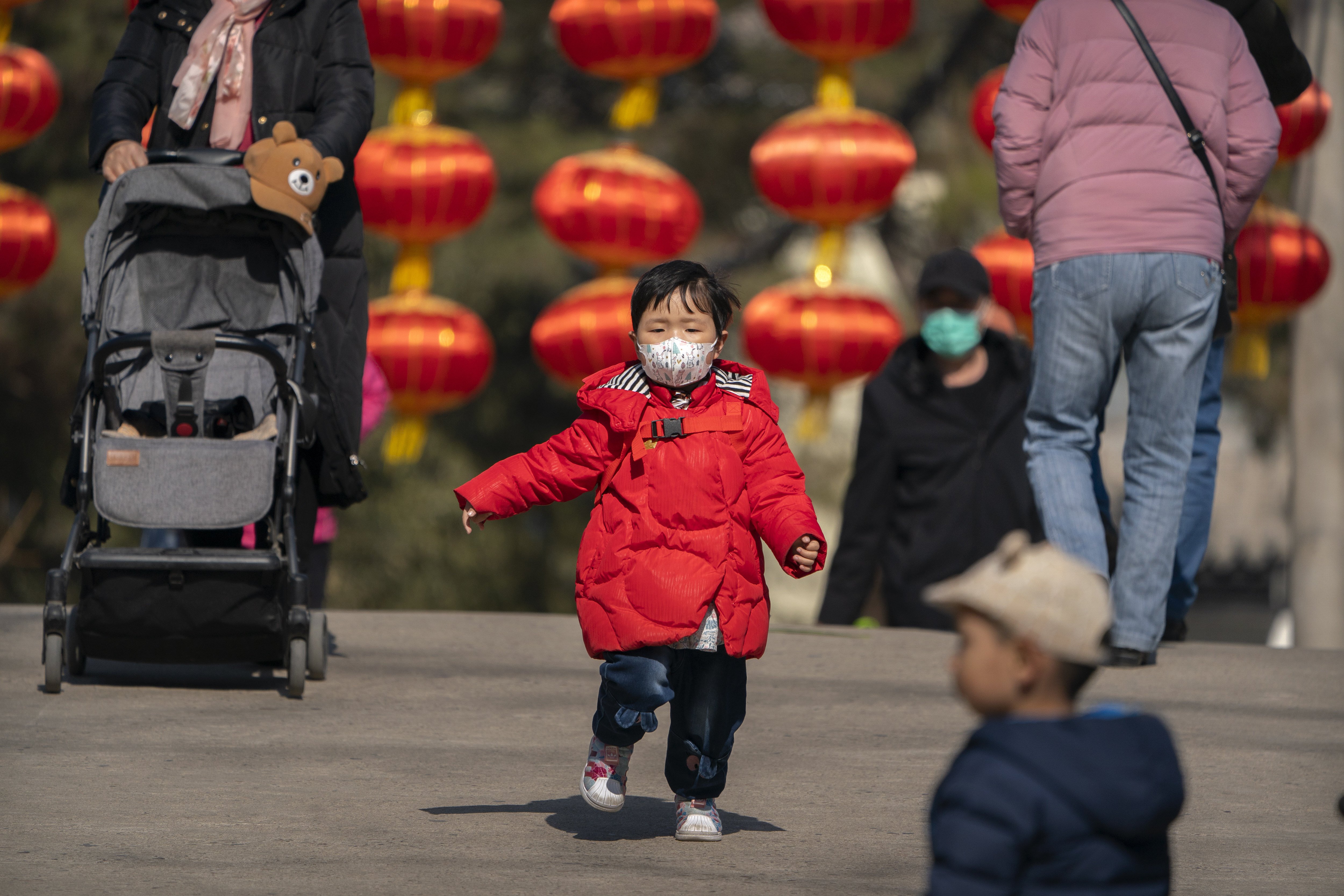 A child wearing a face mask runs along a path in a park in Beijing on February 19. Today, there are more elderly people in China than there are children. Photo: AP