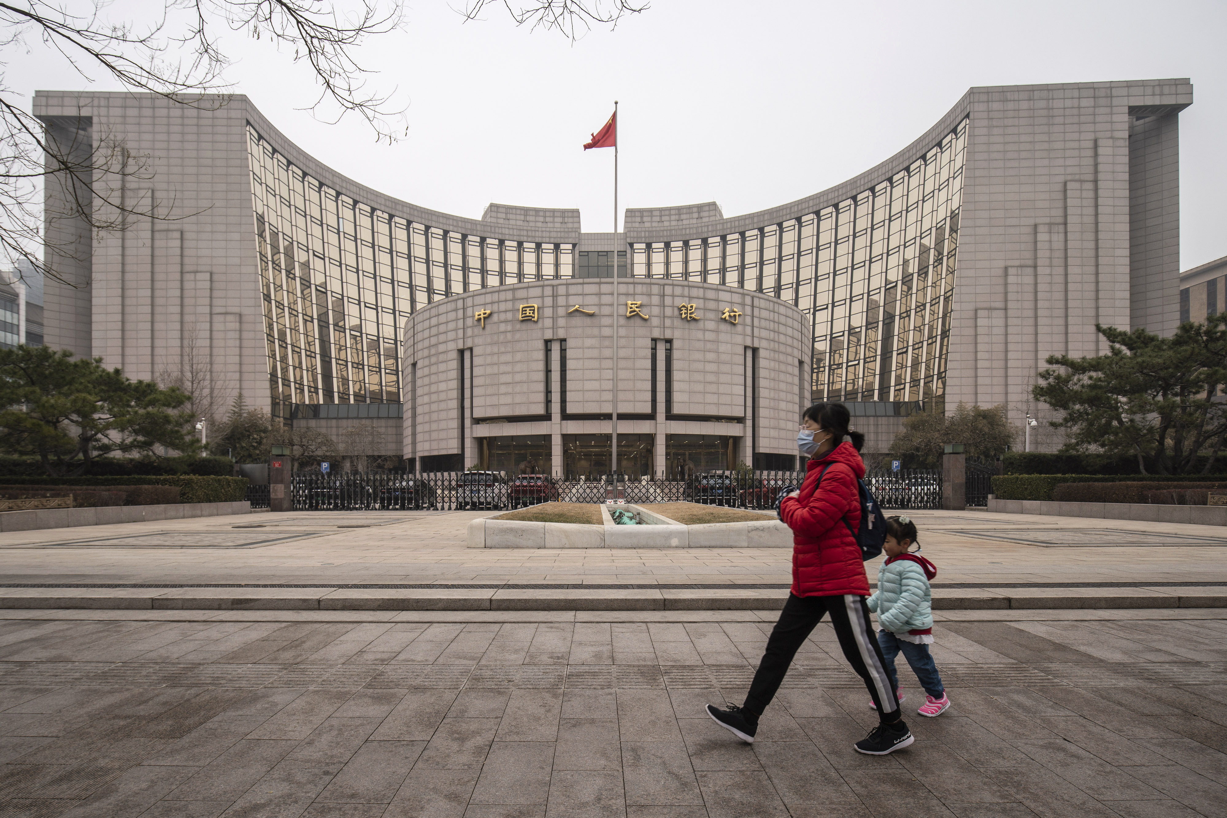 A woman and child walk past the People’s Bank of China building in Beijing, on March 4. Inflationary pressure is unlikely to be a concern for the central bank. Photo: Bloomberg