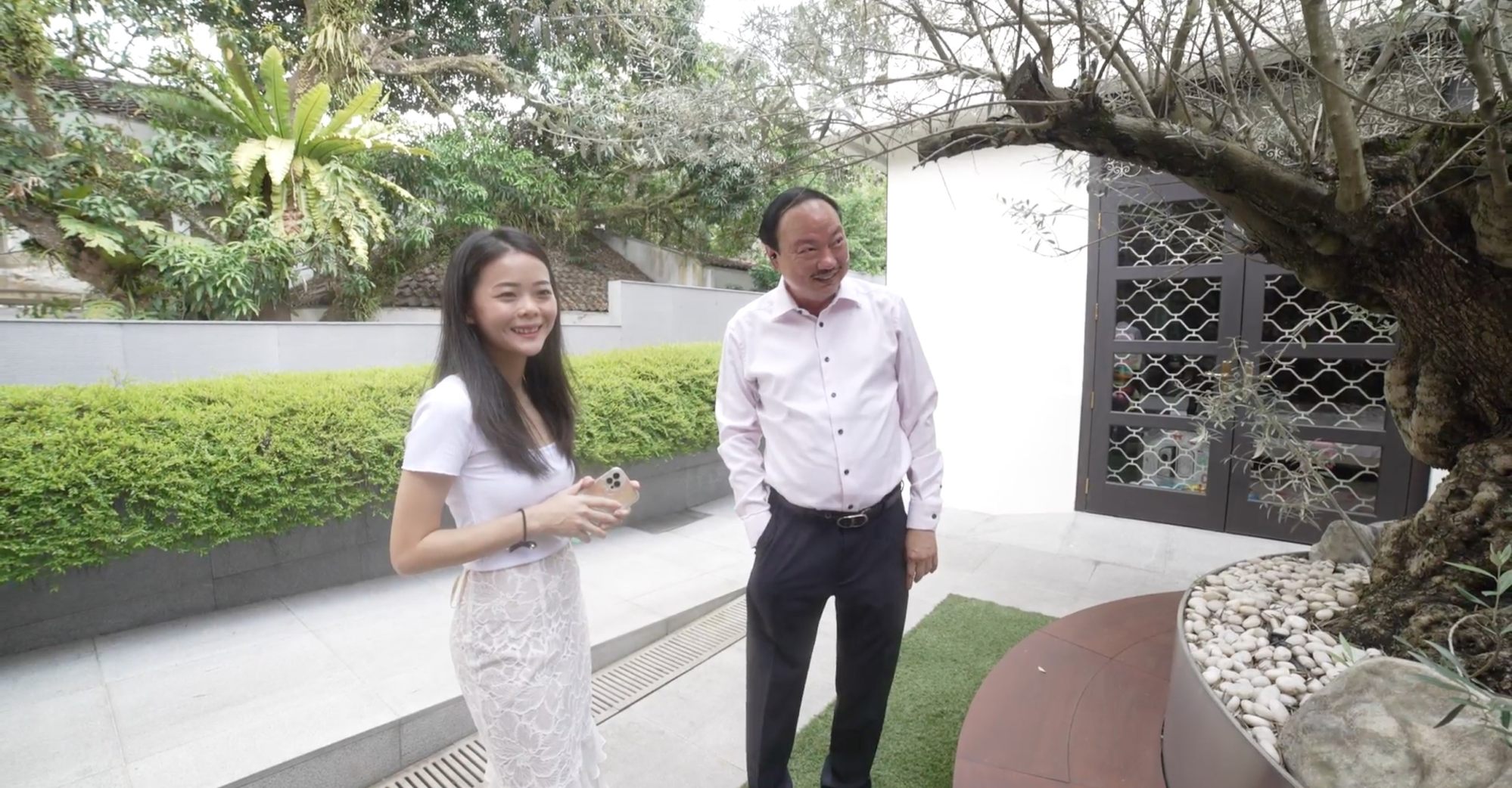Lim Hock Leng and SCMP reporter Kok Xinghui next to a 300-year-old olive tree, which he says is symbolic of the commitment he and his brothers have made to Sheng Siong. Photo: SCMP Pictures