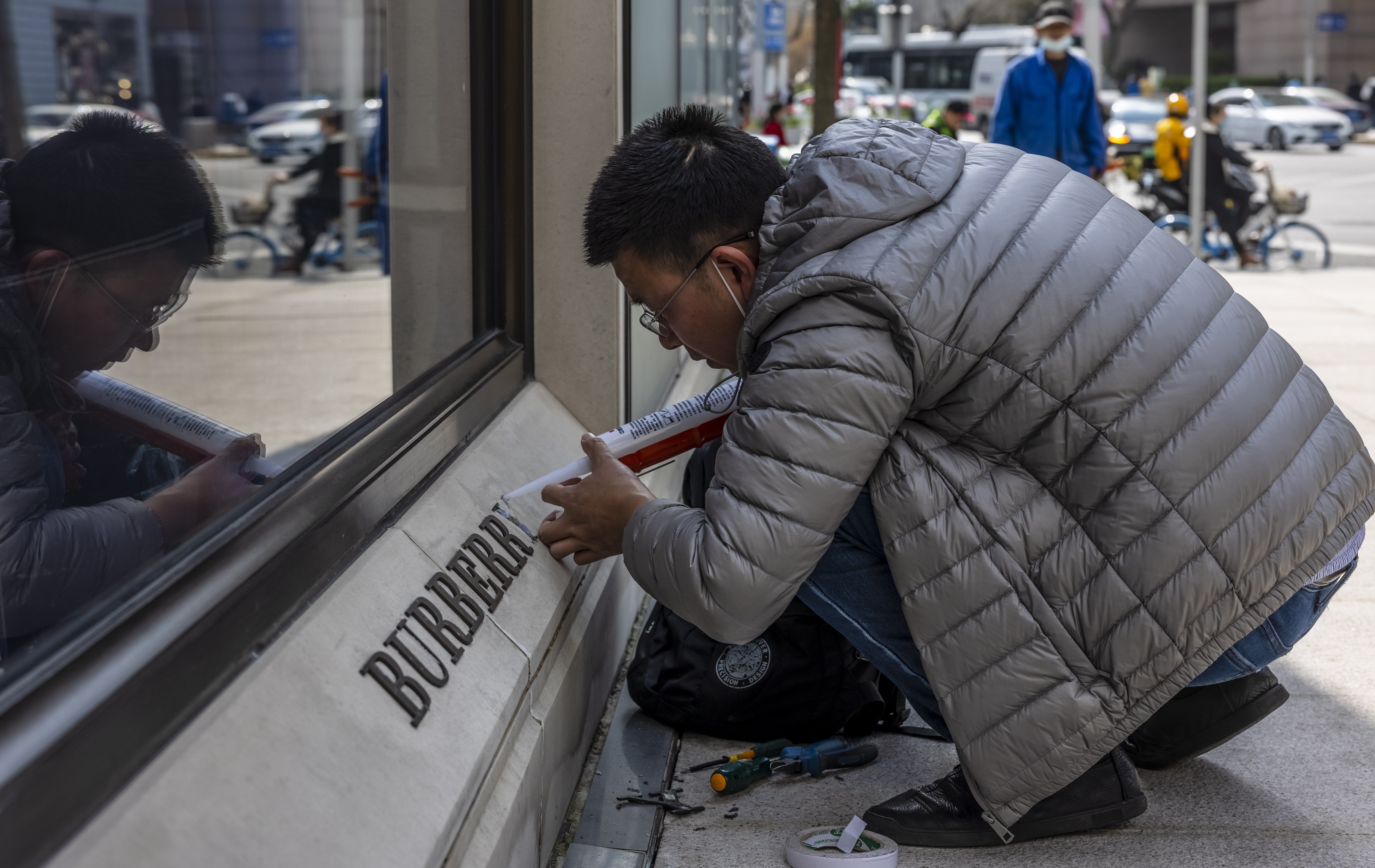 A man repairs a damaged logo in front of the Burberry store in Shanghai on March 26. Burberry,  Fila, Hugo Boss, H&M, Nike and Adidas have been targeted for refusing to buy Xinjiang cotton over concerns of forced labour in the region.  Photo: EPA-EFE