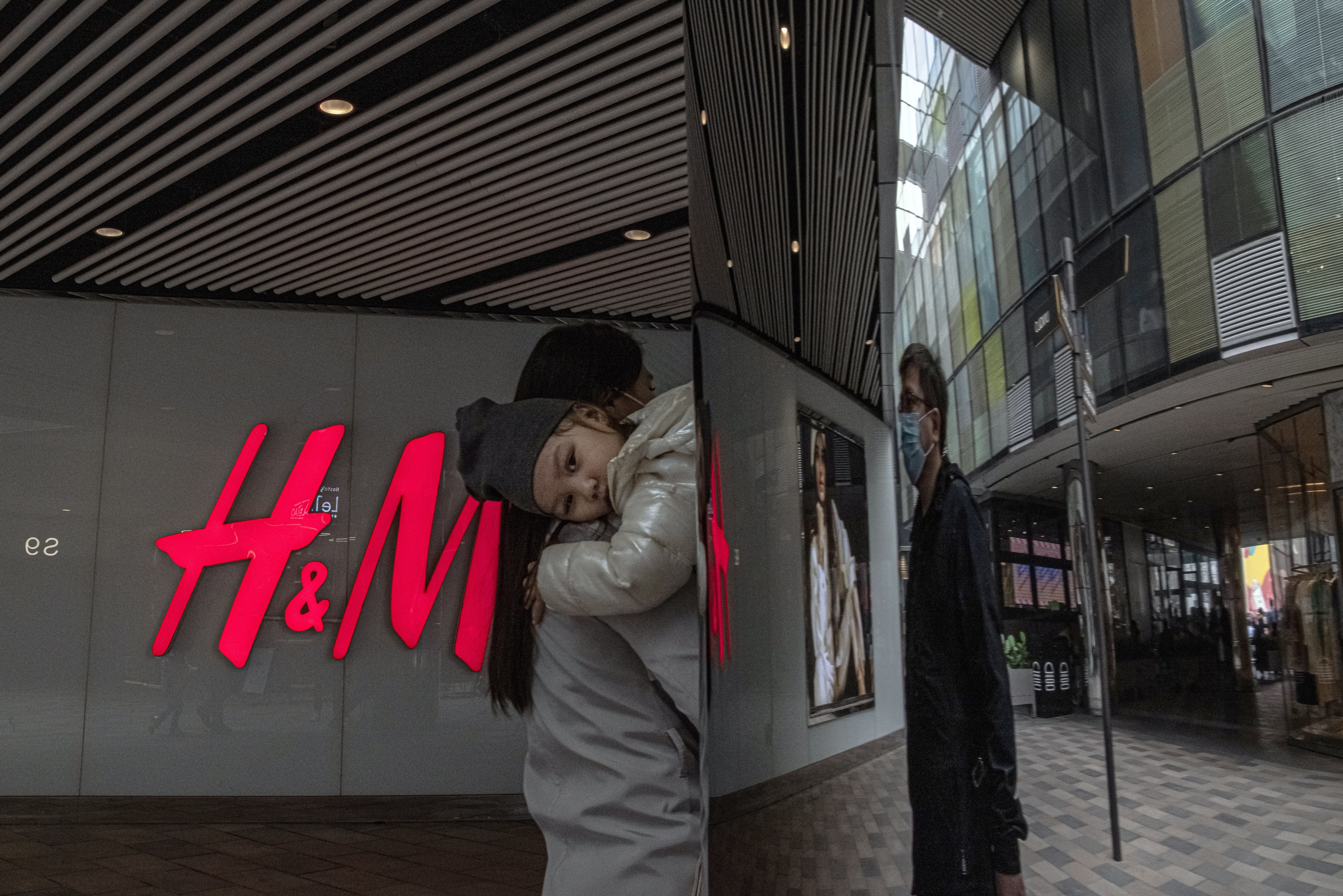 A woman with a child walks past an H&M store in Beijing, on March 27. Photo: EPA-EFE