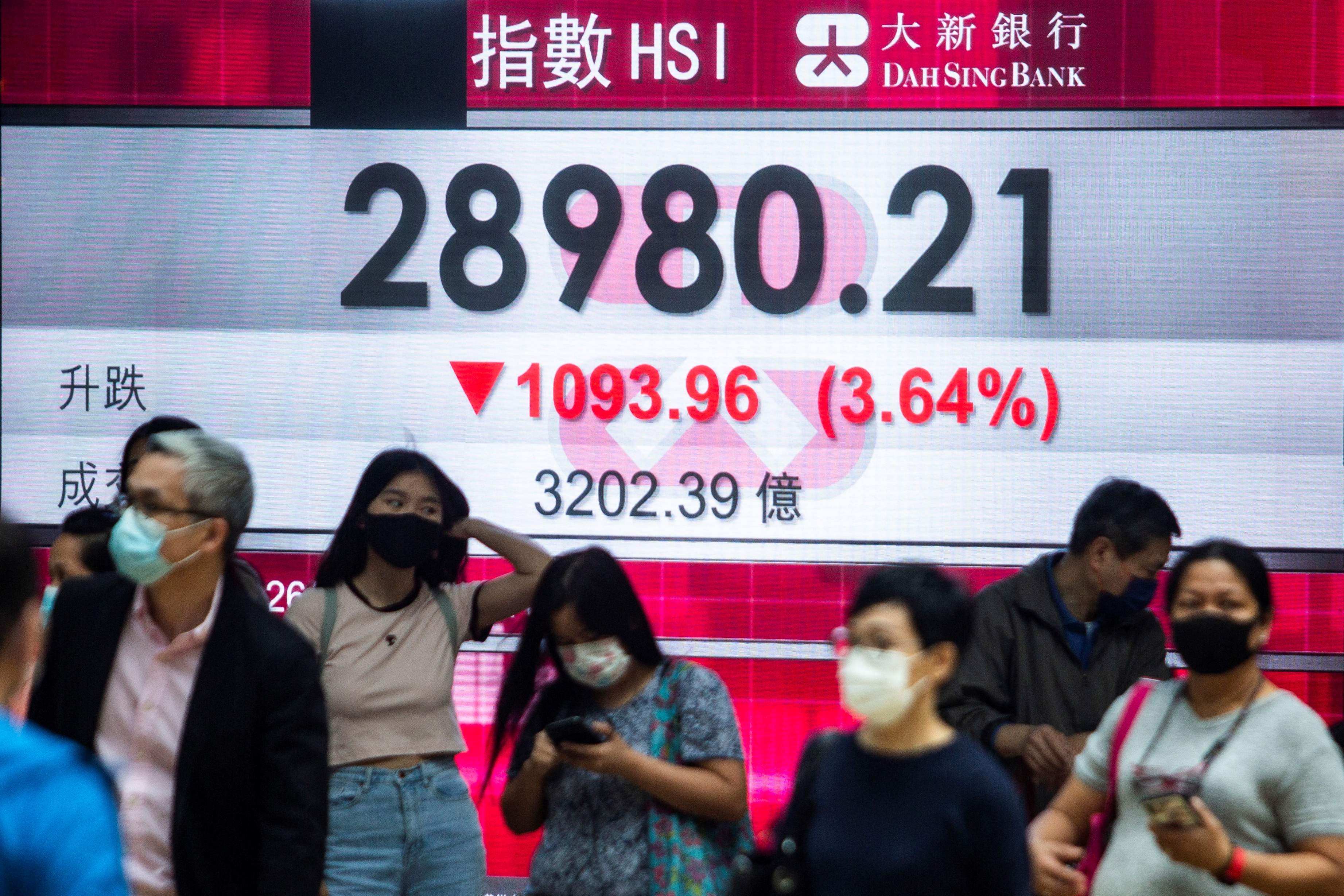 People walk past an electronic display showing the Hang Seng Index in Hong Kong’s Central district on February 26. Photo: AFP