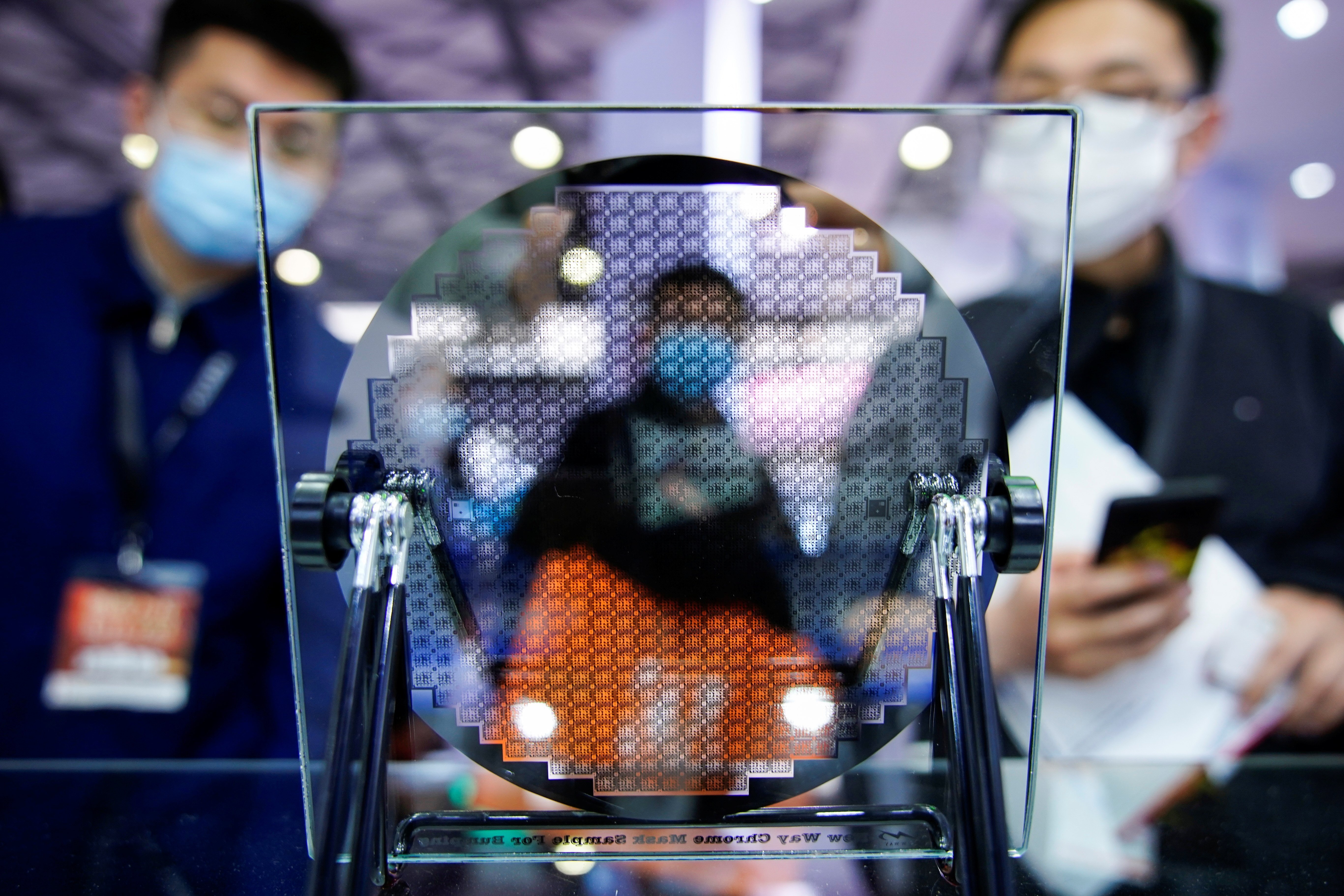 Visitors look at a display of a semiconductor device at Semicon China, a trade fair for semiconductor technology, in Shanghai, China March 17, 2021. REUTERS/Aly Song