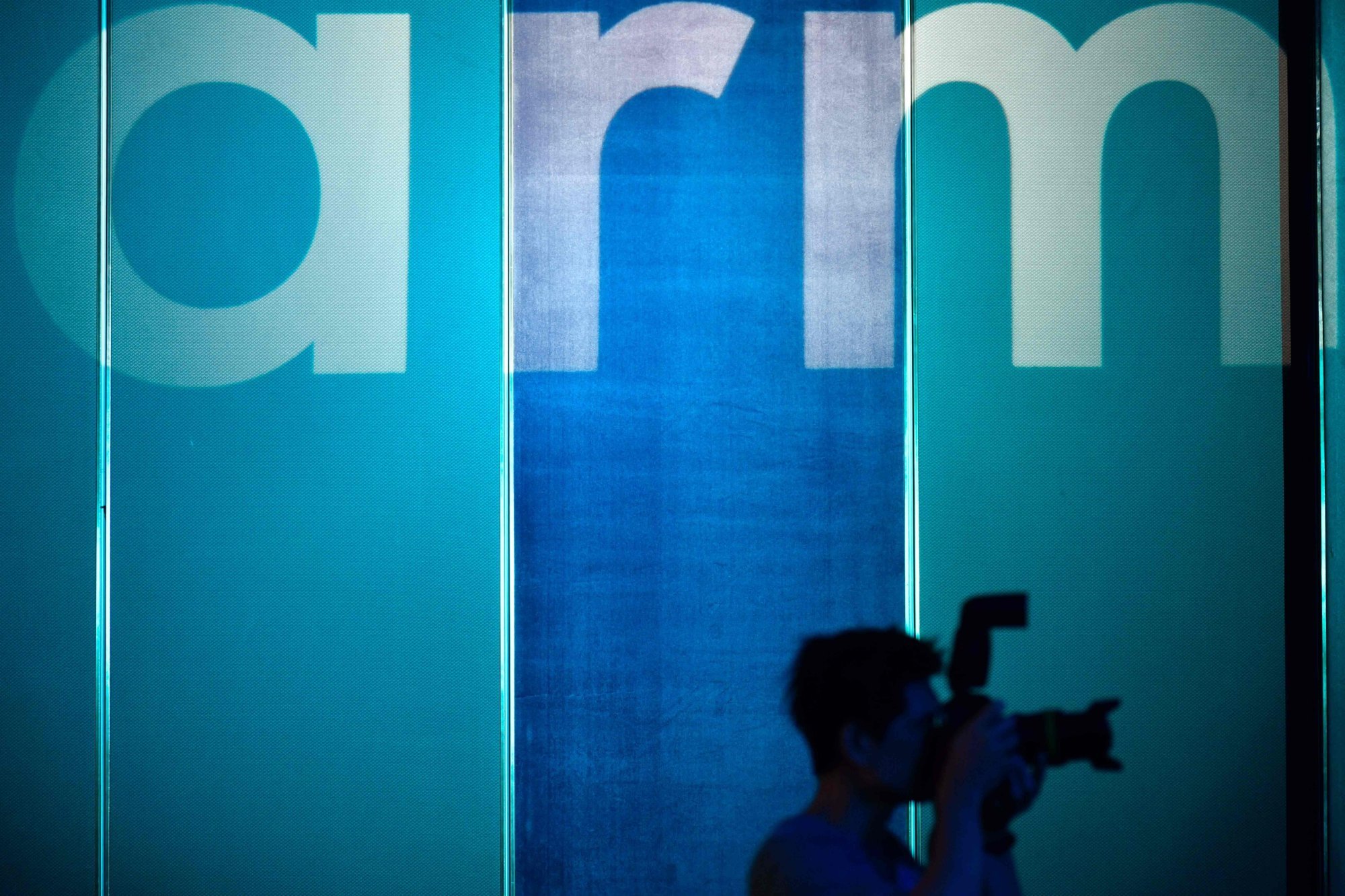 A photographer taking pictures in front of the logo for British chip designer ARM in Taipei on May 27, 2019. Photo: AFP