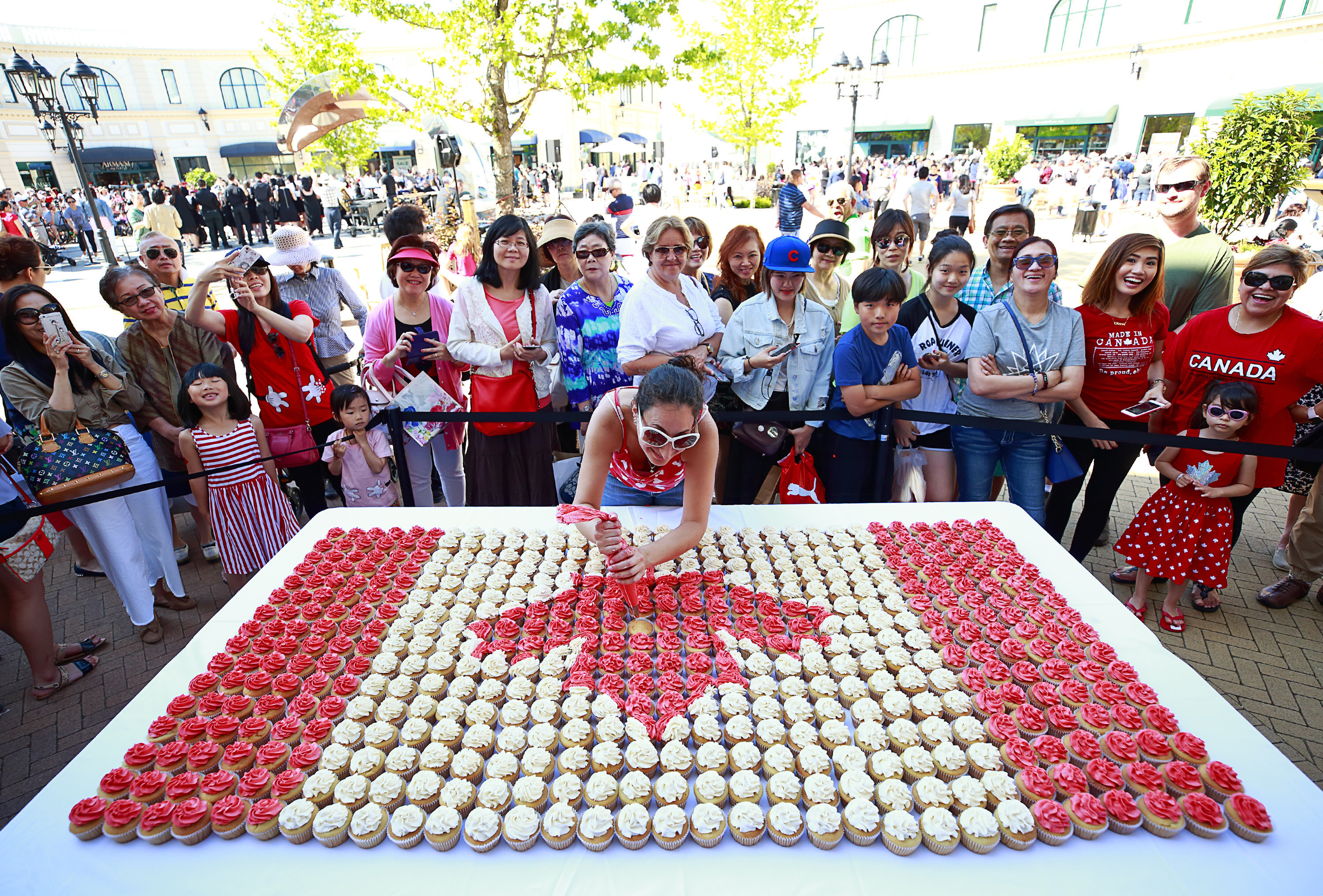 A crowd watches cupcakes being iced in the form of  a Canadian flag during Canada Day celebrations in Richmond, British Columbia, on July 1, 2017. Richmond is the most ethnically Chinese city in the world outside Asia, and home to large numbers of Hong Kong and mainland Chinese immigrants. Photo: AFP 