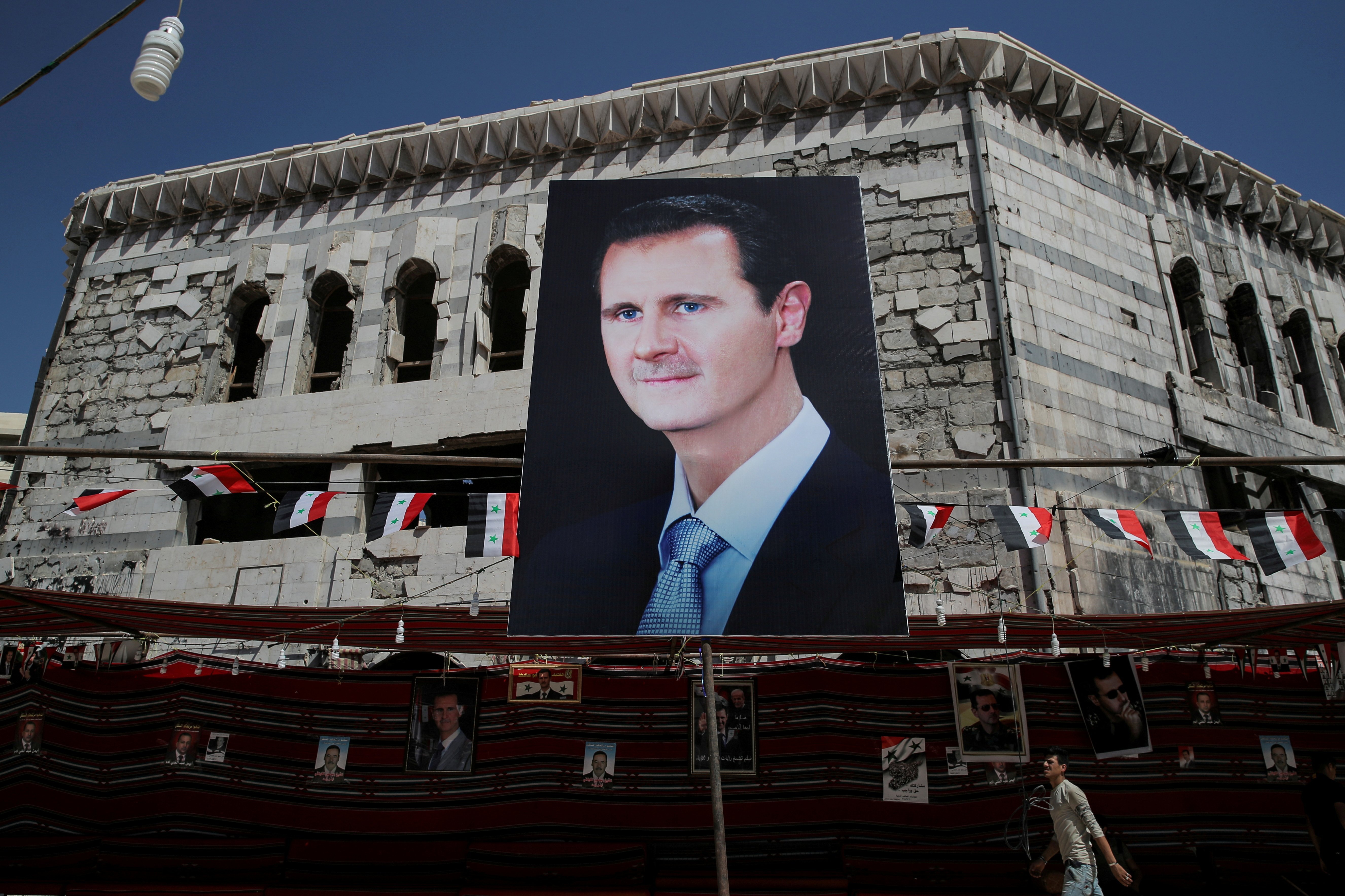 A man walks past a banner depicting Syrian president Bashar al-Assad in Douma, outside Damascus, in September 2018. Photo: Reuters