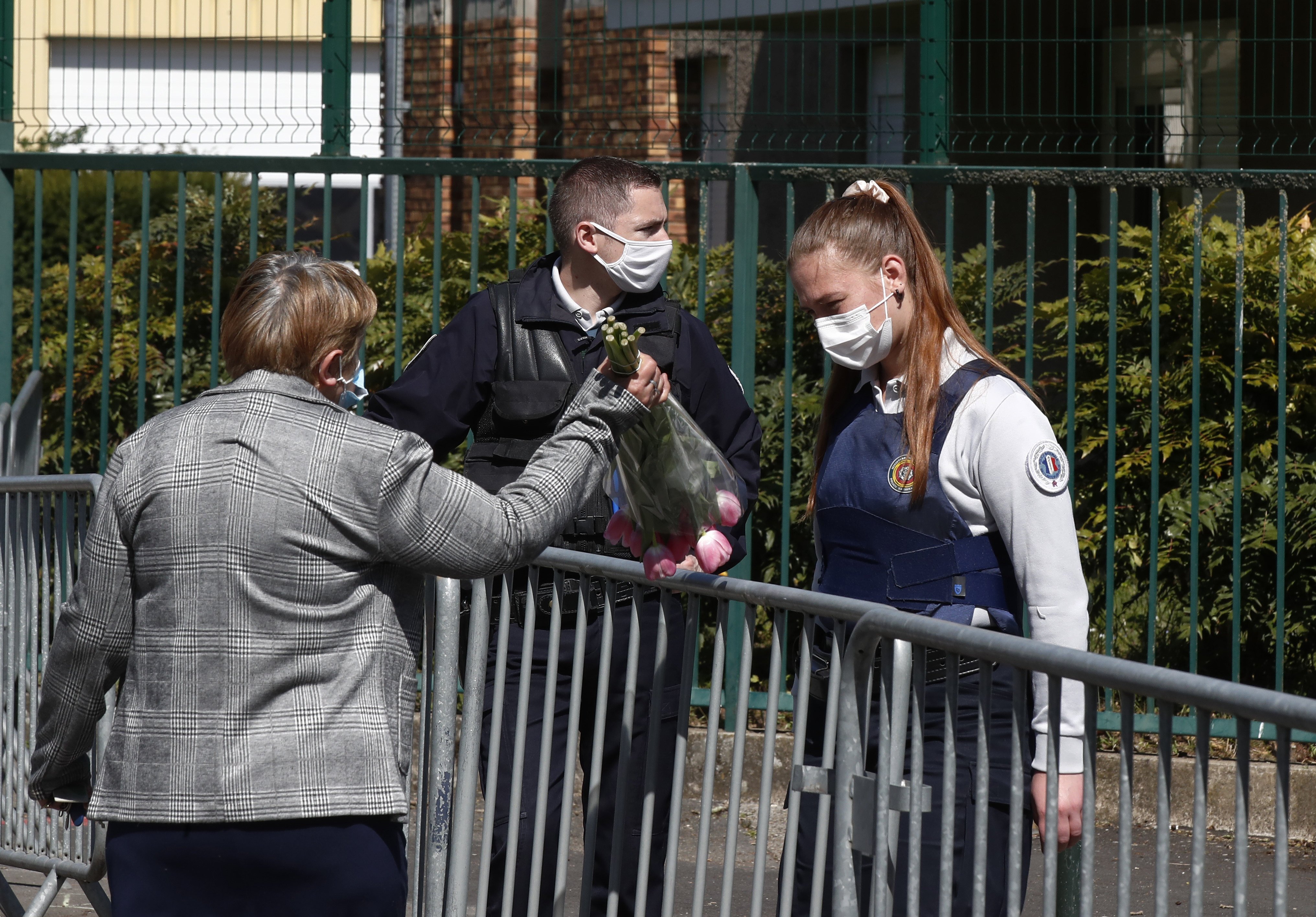 A woman hands flowers to a police officer in Rambouillet, near Paris, on Saturday. Photo: AP 