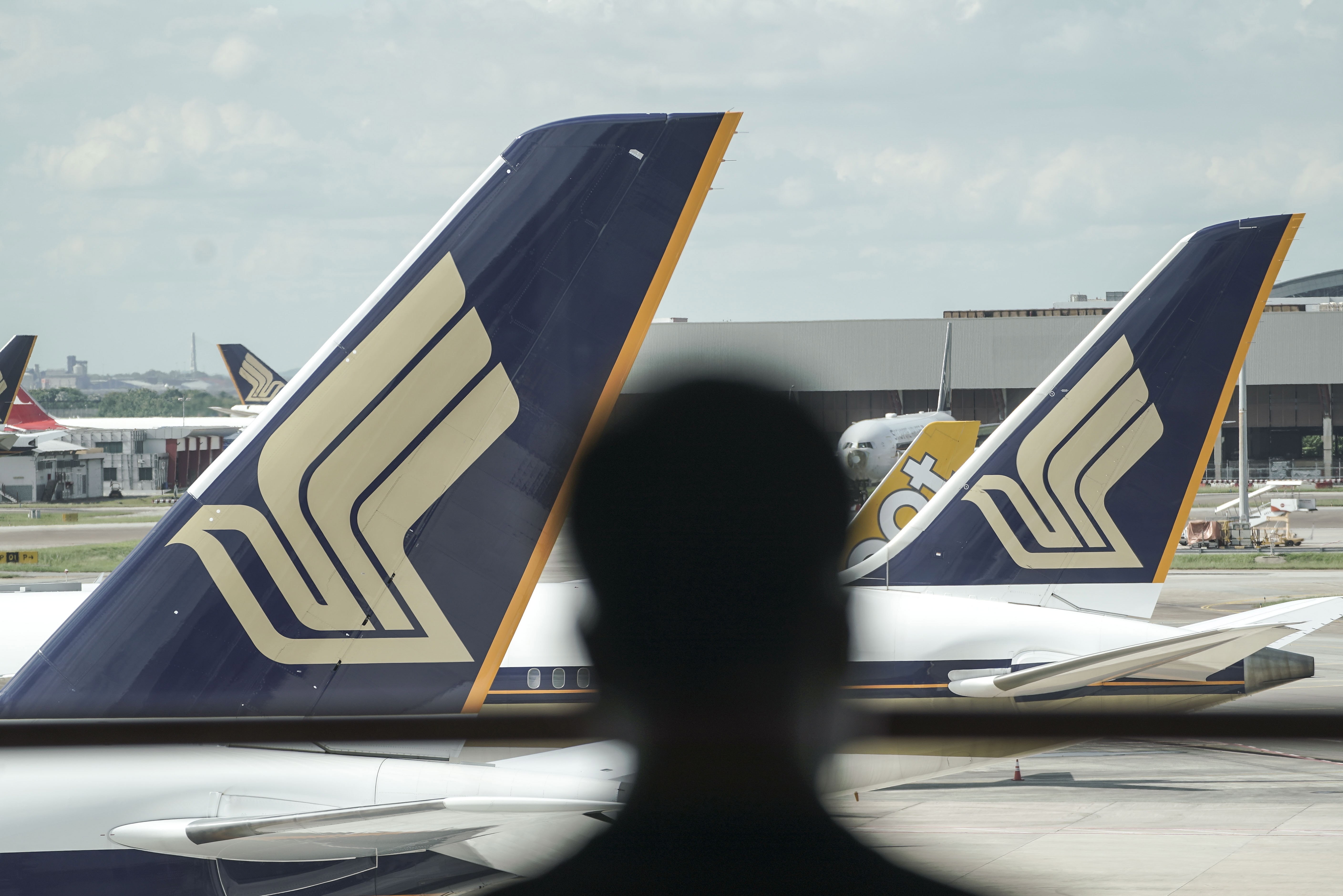 A man is silhouetted against a pair of Singapore Airlines commercial jets at Changi Airport. Photo: EPA-EFE