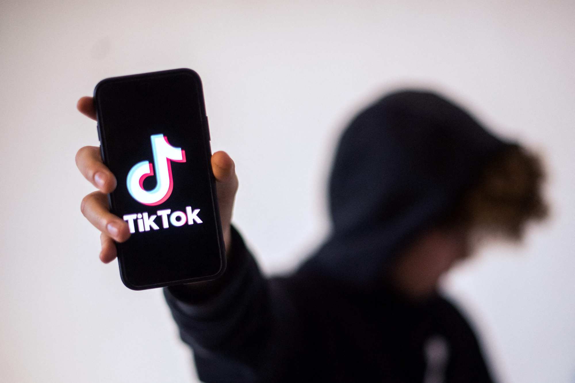 A teenager poses presenting a smartphone with the logo of social network TikTok in Nantes, western France, on January 21, 2021. Photo: AFP