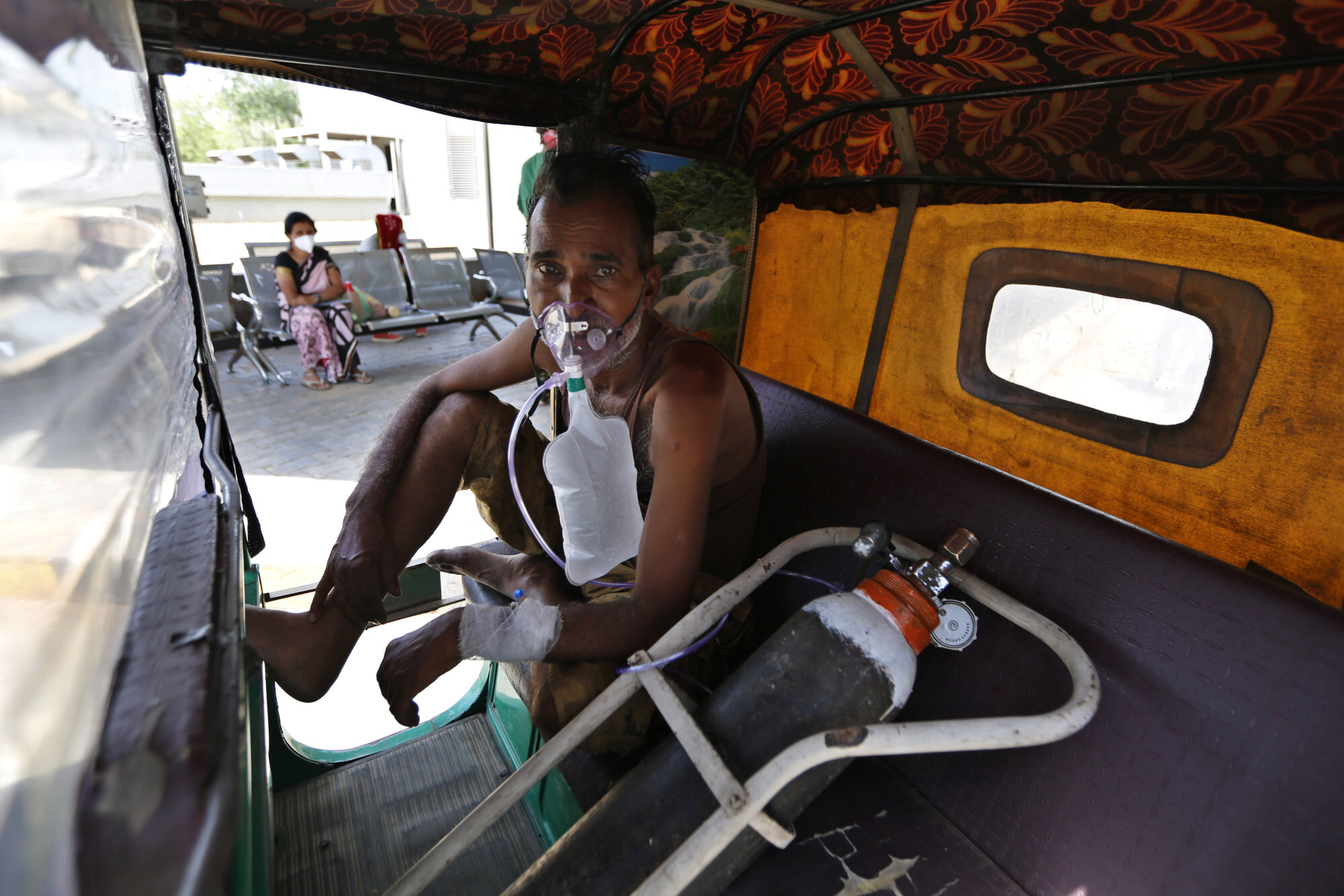A Covid-19 patient breathes with the help of an oxygen mask as he waits inside an auto rickshaw to be admitted in a government hospital in Ahmedabad. Photo: AP