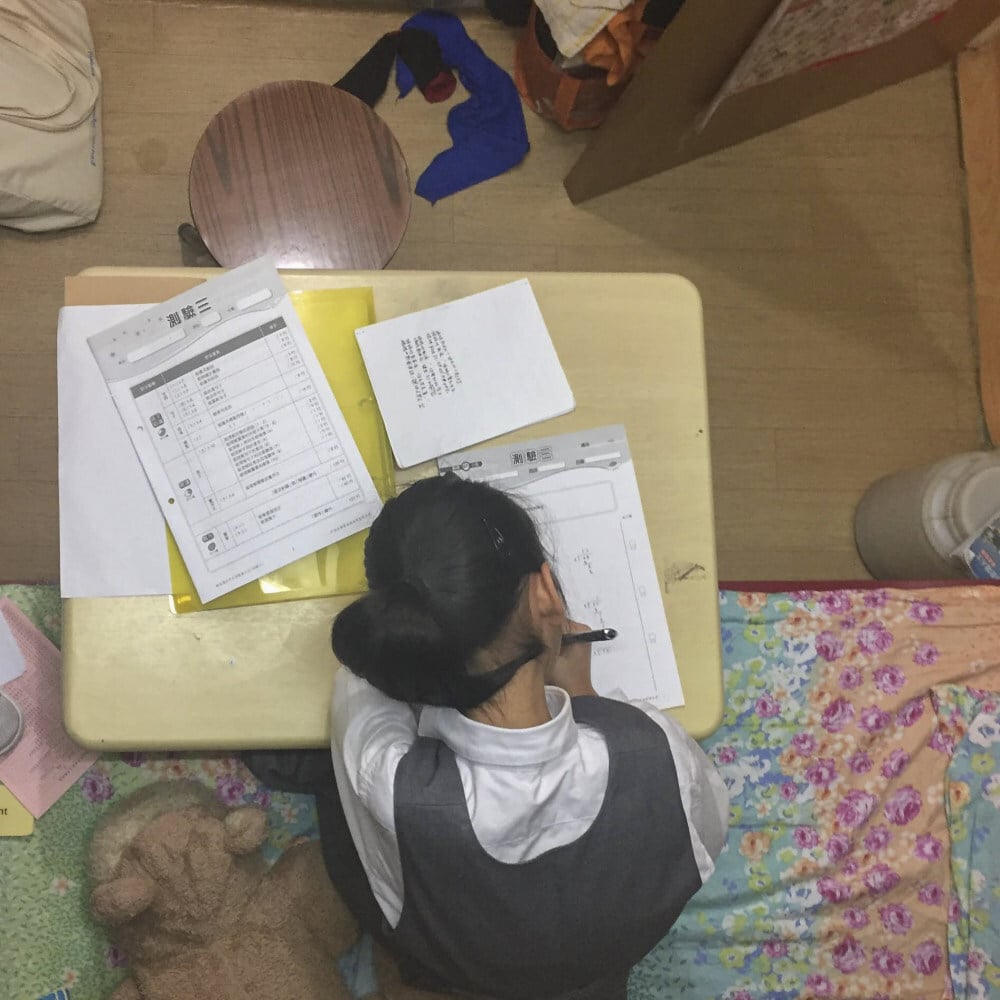 A student, Alice, does her homework in the subdivided home she shares with her mum. Photo: Elaine Lok