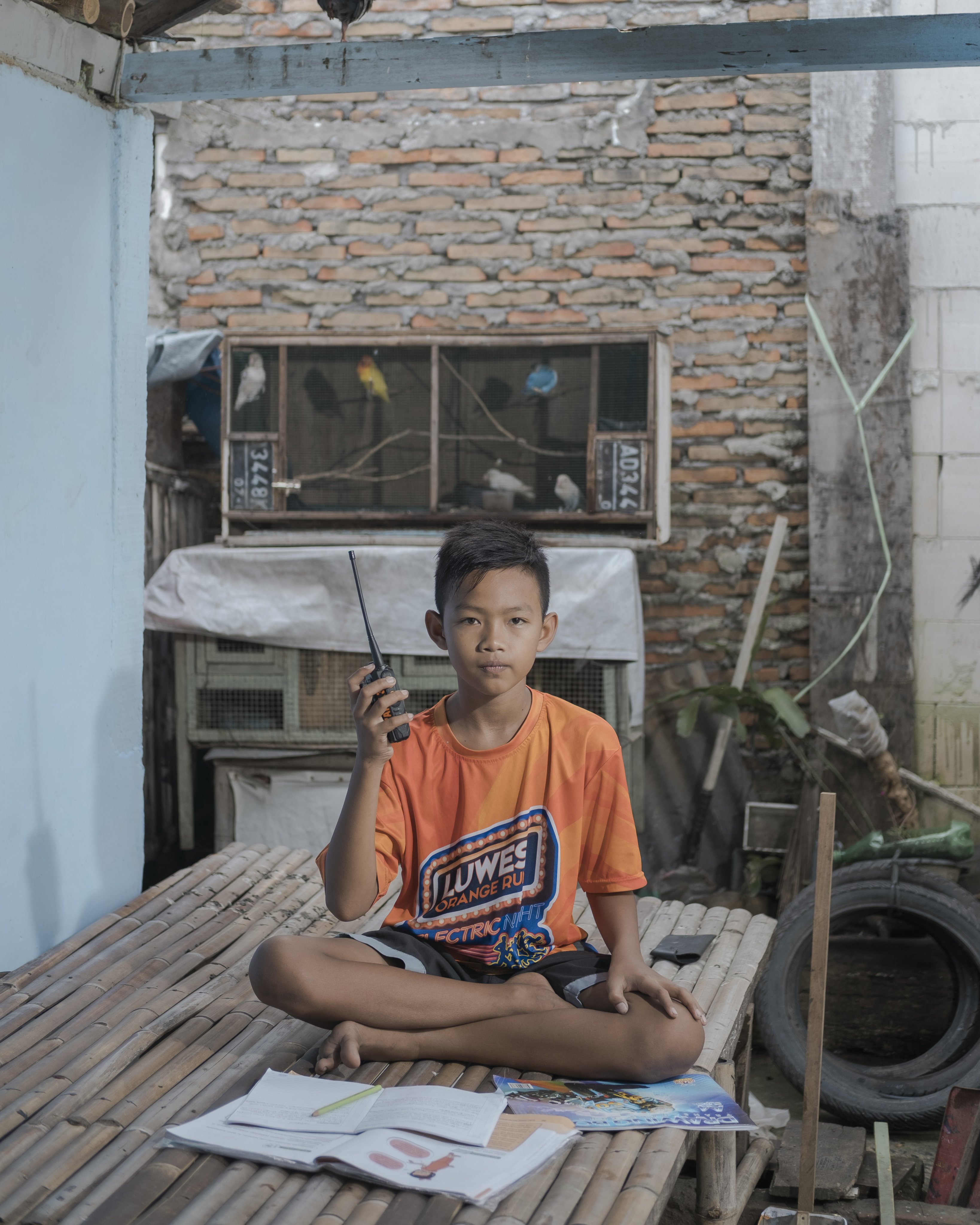 Fahri Yulianto, 11, listens to school lessons using a walkie-talkie in Surakarta, Indonesia. “At first, my teacher announced that we would study at home for two weeks, not expecting that it would be extended to more than a year until now. I’m looking forward to school reopening soon,” he says. Photo: Agoes Rudianto