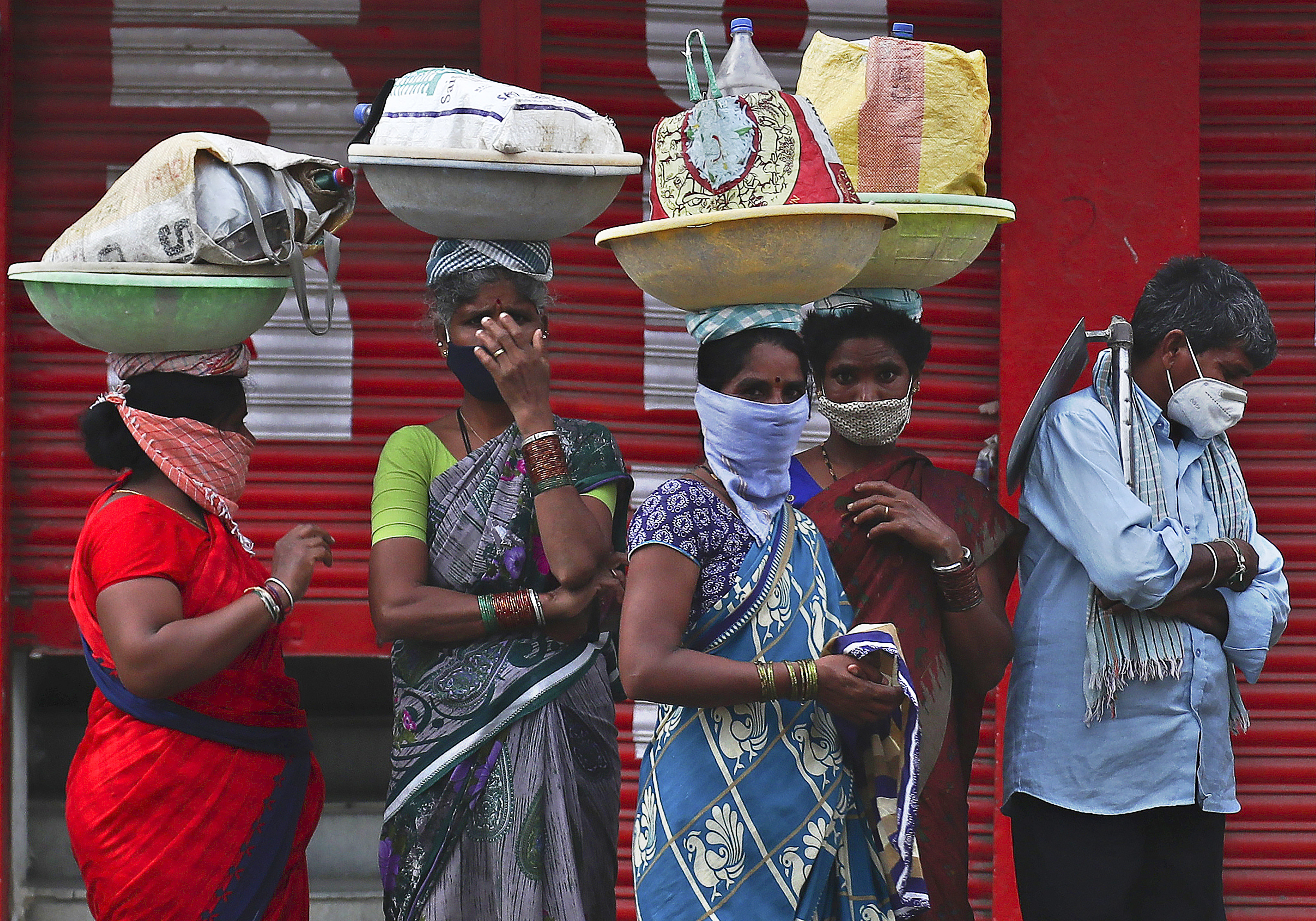 Labourers wearing protective face masks wait for transport to work in Hyderabad, India. Photo: AP