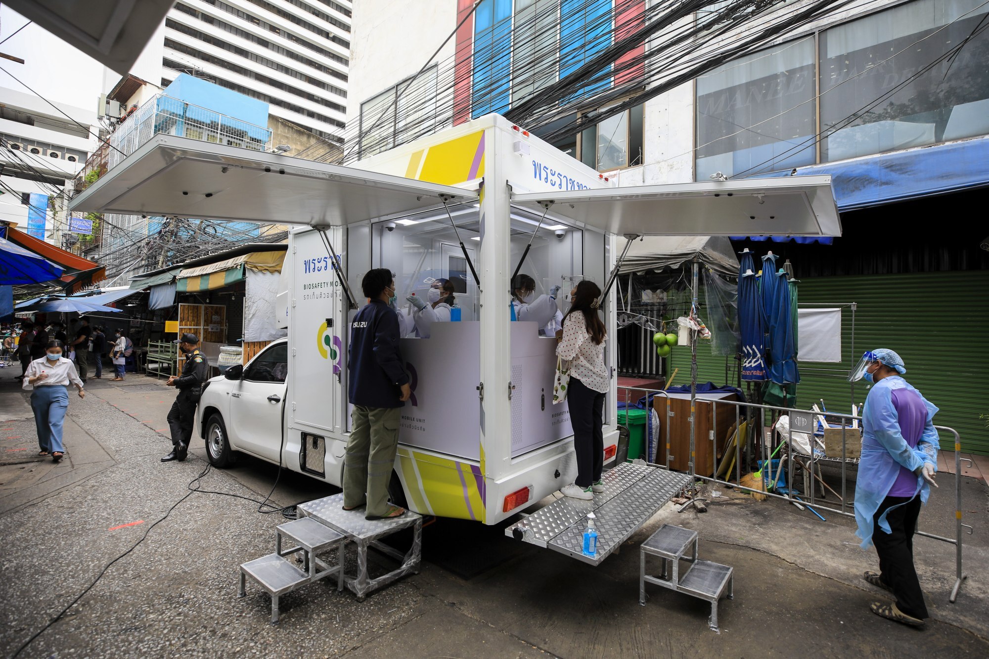 Thai health officials collect samples during a community nasal swab test drive at a local street market in Bangkok, Thailand. Photo: EPA