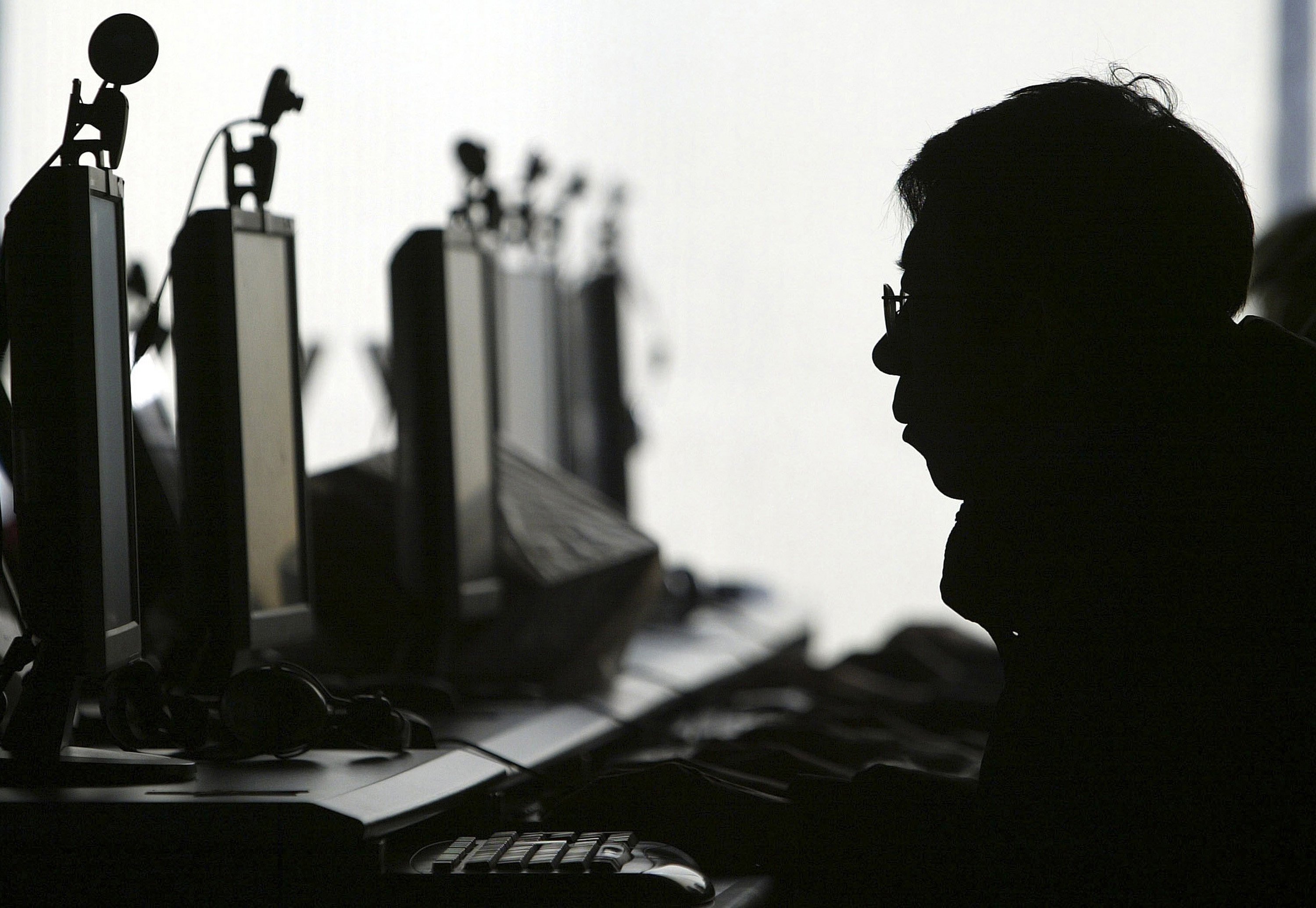 A computer user is silhouetted with a row of computer monitors at an Internet cafe in Shenyang, in northern China’s Liaoning province on January 28, 2008. Photo: AP