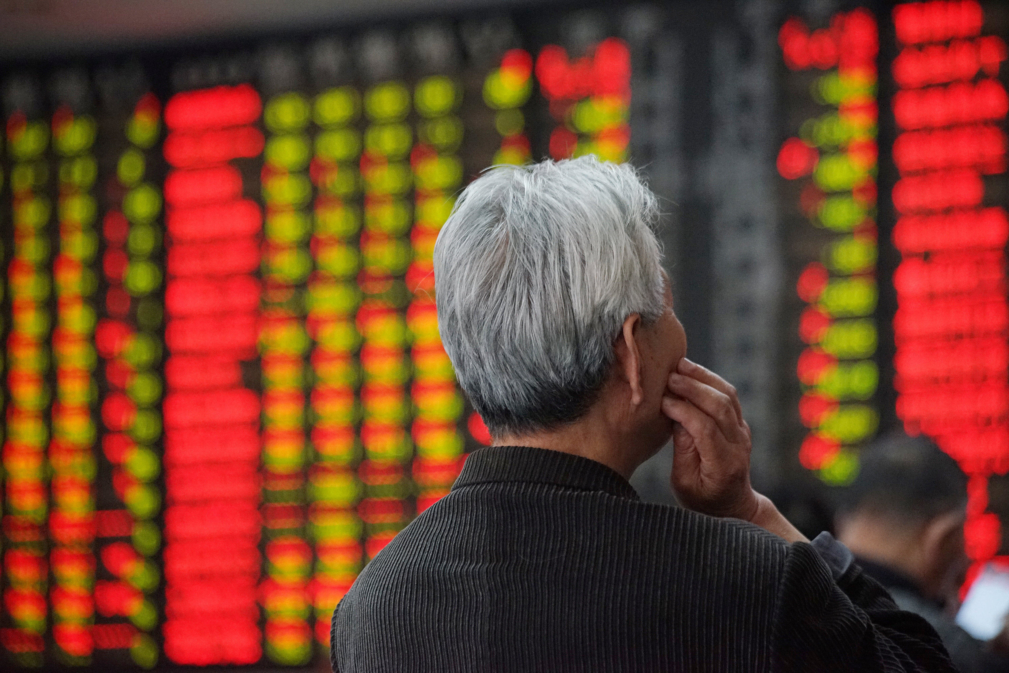 An investor looks at an electronic board showing stock information at a brokerage house in Nanjing, Jiangsu province. Photo: Reuters