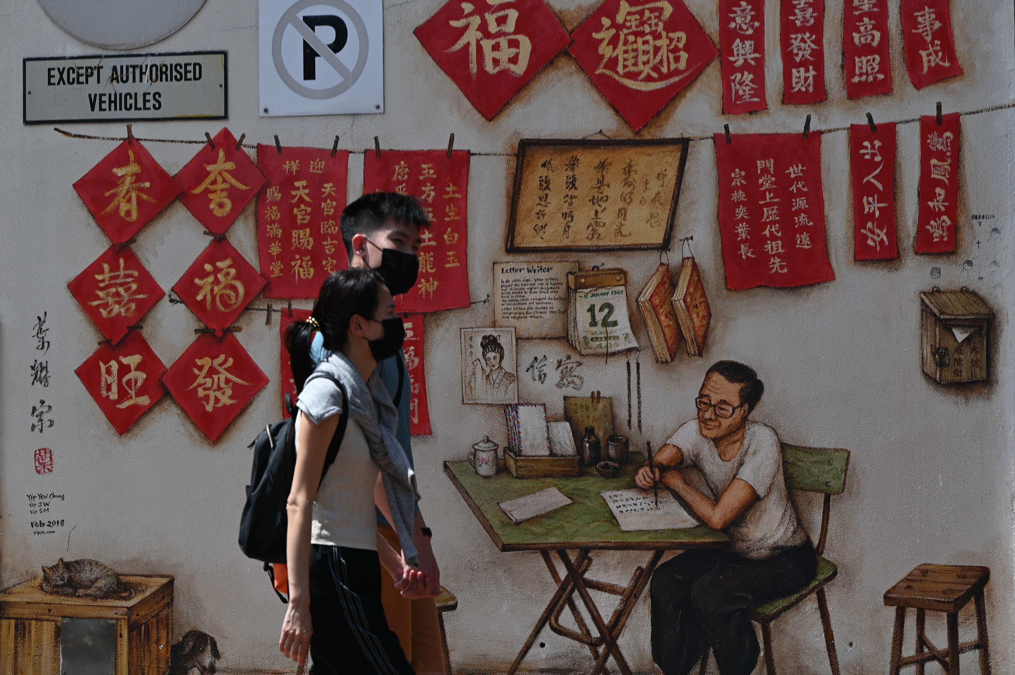 A couple walk past wall murals in a back alley in the Chinatown area of Singapore. Photo: AFP