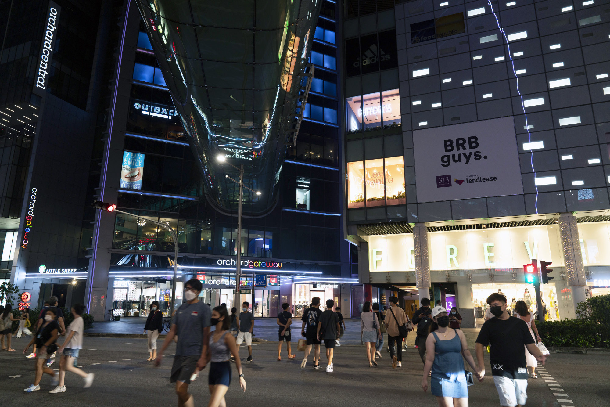 Pedestrians cross the road in front of shopping malls on Orchard Road in Singapore earlier this month. Photo: Bloomberg