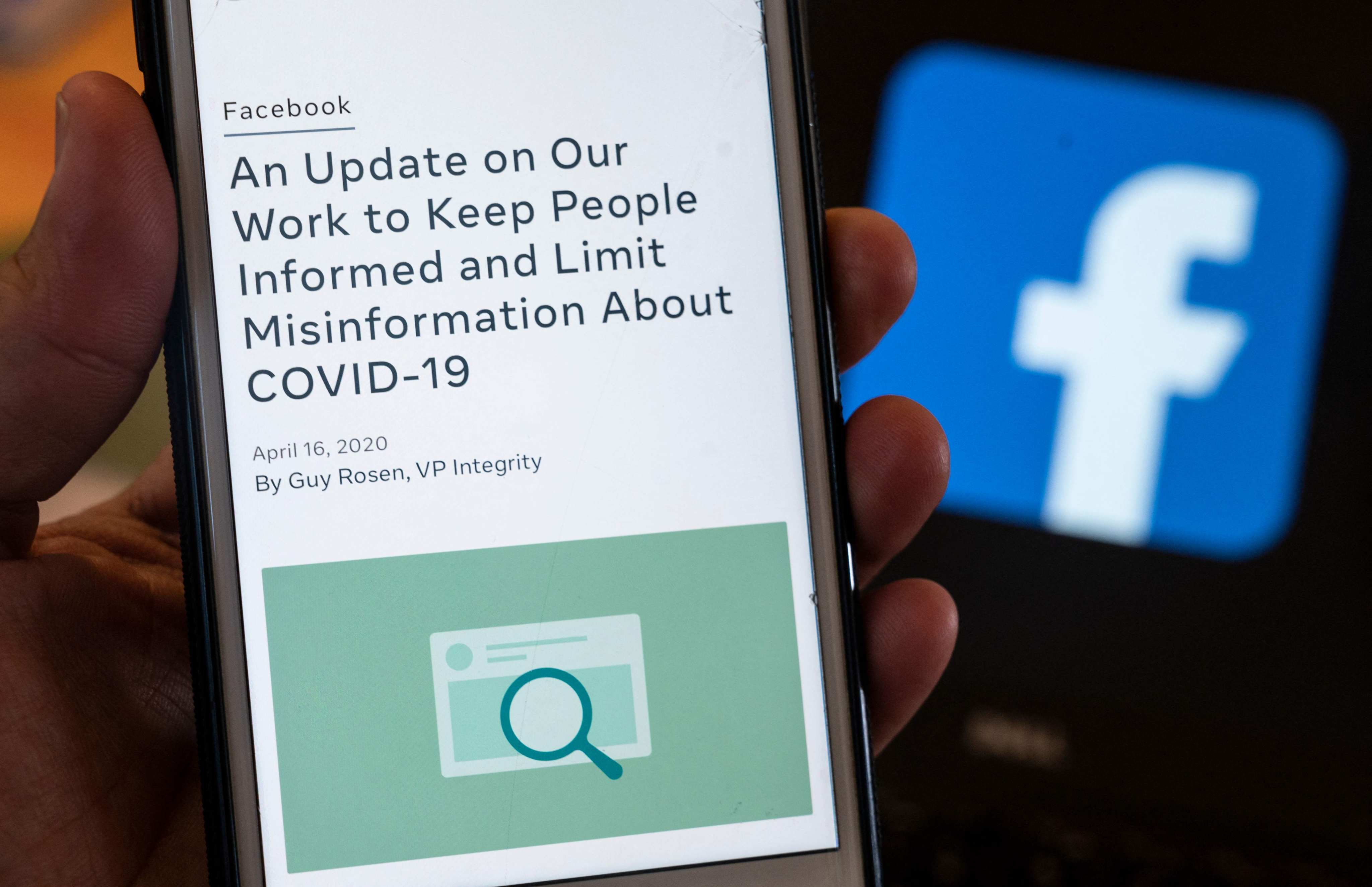 A smart phone screen displays a new policy on Covid-19 misinformation with a Facebook website in the background. Facebook is one of the digital platforms that have adopted the Australian Code of Practice on Disinformation and Misinformation. Such voluntary codes are an essential tool in fighting fake news. Photo: AFP