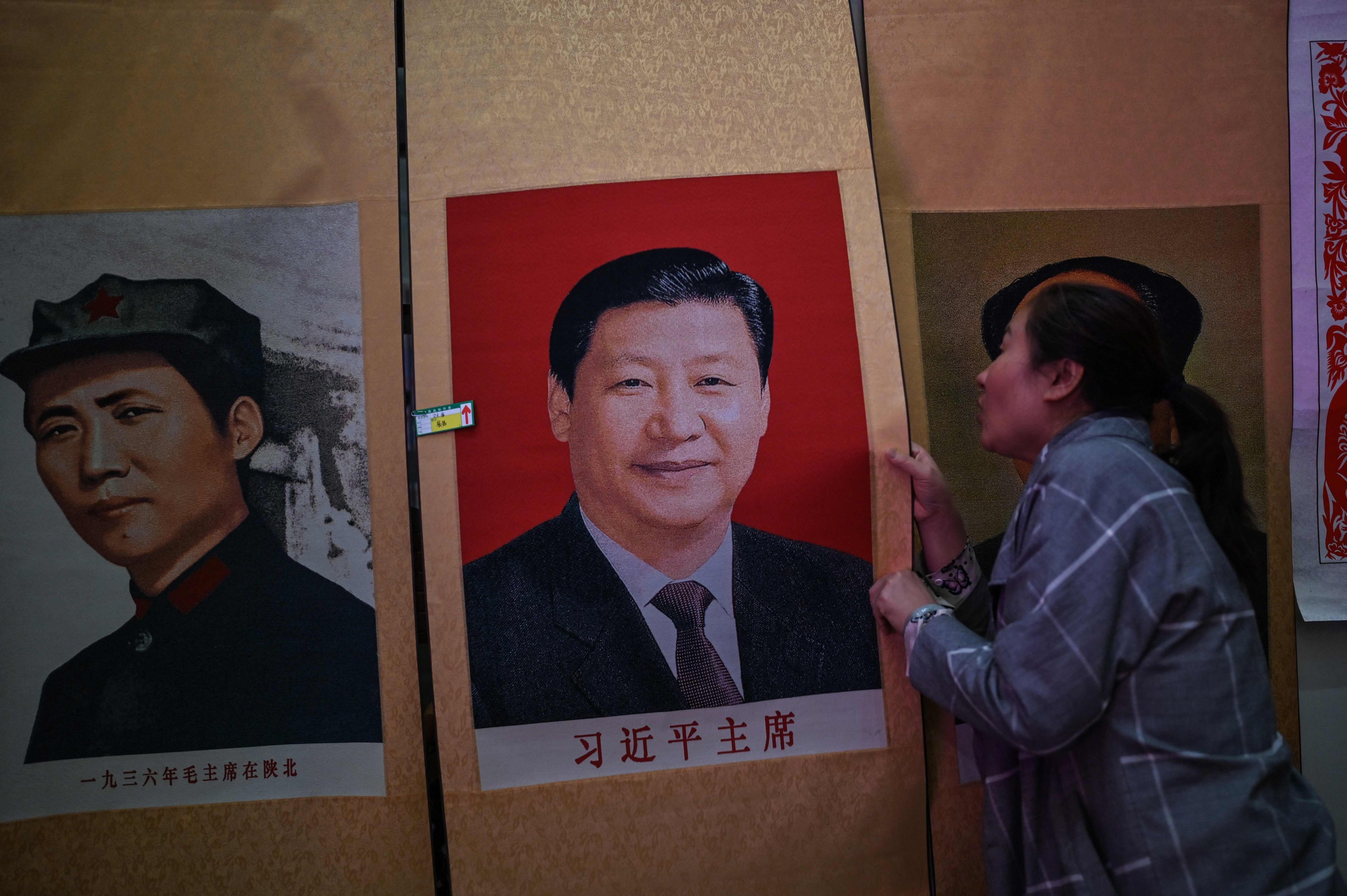 A seller holds a portrait of Chinese President Xi Jinping next to a picture of former Chinese leader Mao Zedong at Dongfanghong Theatre in Yan’an. Photo: AFP