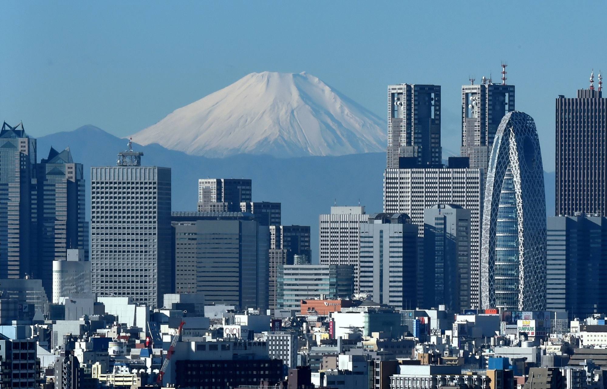 Japan’s highest mountain, Mount Fuji, rises above the skyline of the Shinjuku area in Tokyo in December 2014. Although rents are under pressure, the city’s office vacancy rate remains low. Photo: AFP
