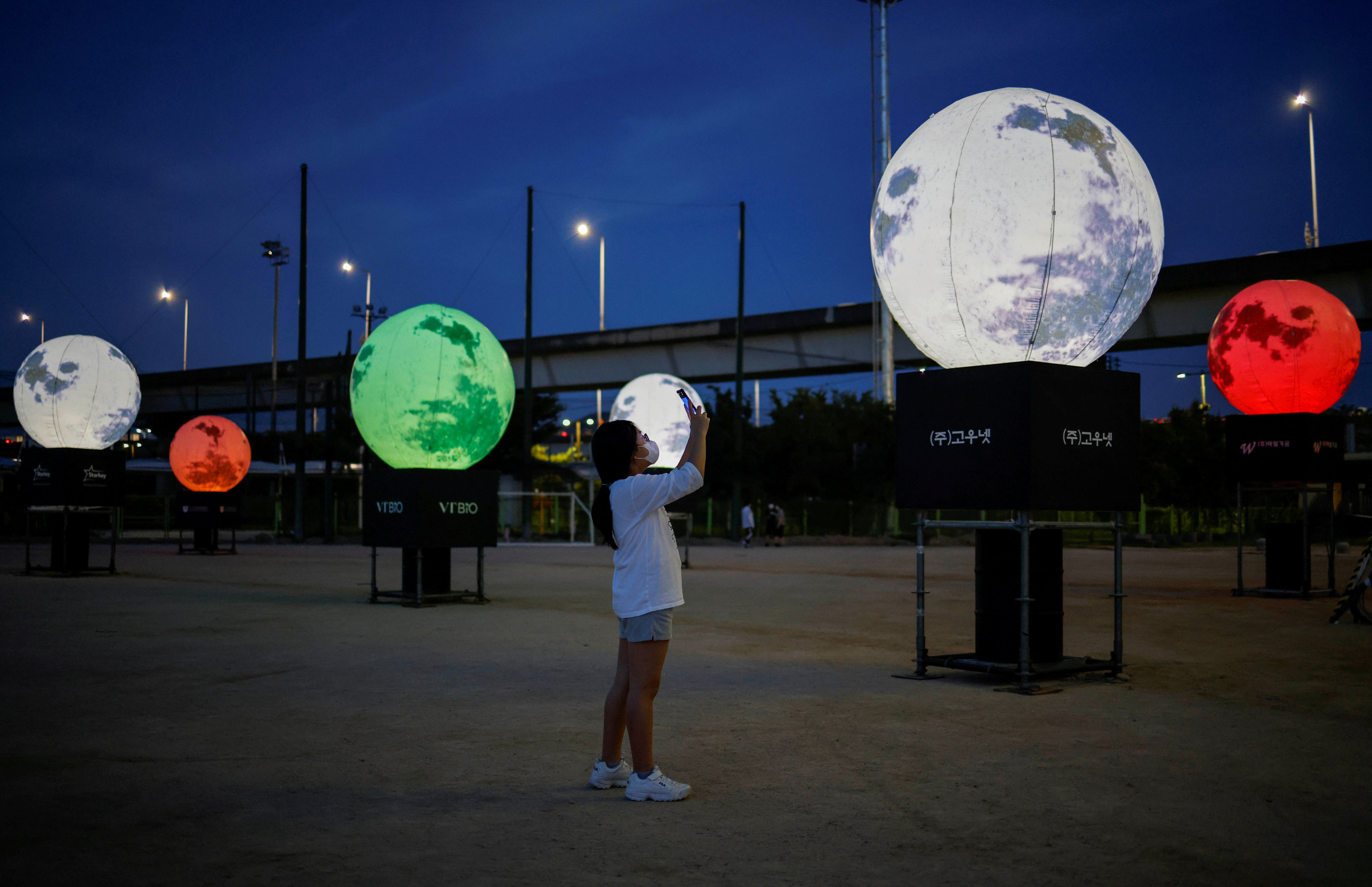 A girl takes a picture of artificial full moons installed at a park as a wish to overcome the coronavirus pandemic and celebrate the Chuseok holiday, the Korean Thanksgiving Day, in Seoul, South Korea, on September 21, 2020. While national rivalries fostered innovation during the Cold War space race, they can also stymie it. Photo: Reuters