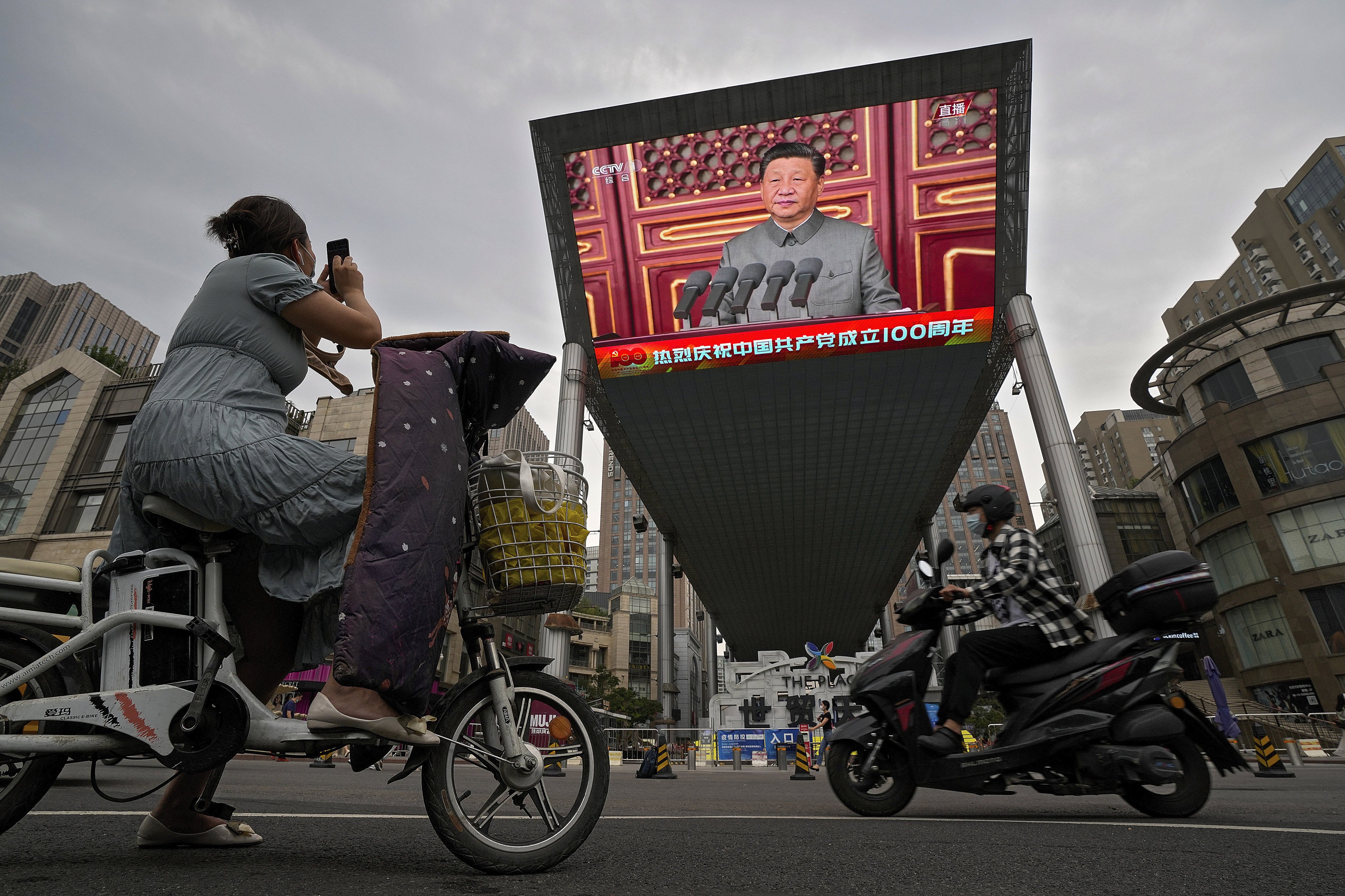 A woman on an electric scooter films a large screen outside a shopping mall showing President Xi Jinping’s speech on the 100th anniversary of China’s Communist Party on July 1. Although the speech was intended for the domestic audience, it was bound to have an international effect. Photo: AP 