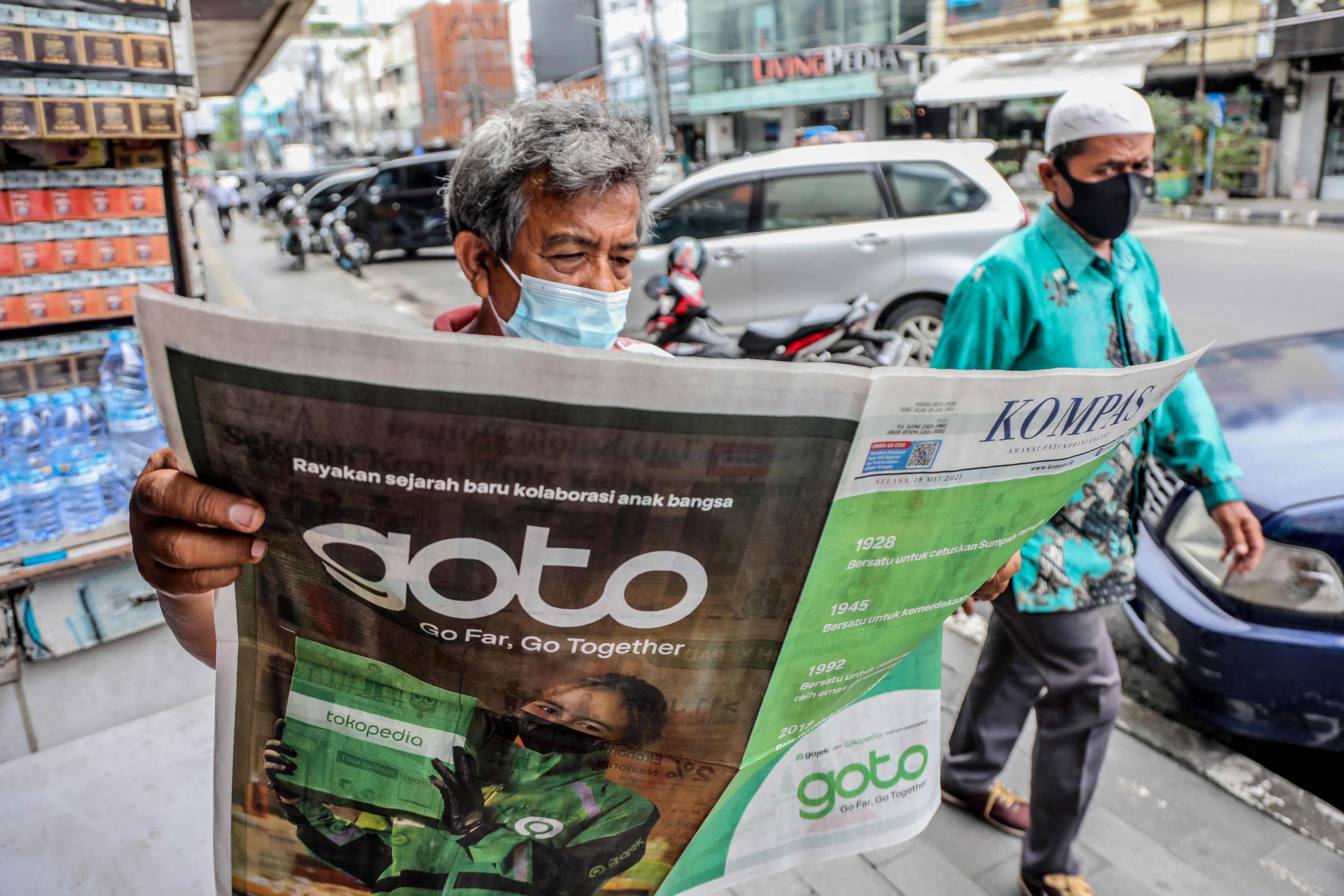 A man reads a newspaper with an advertisement of the Gojek-Tokopedia merger in Medan, Indonesia, on May 18. The resulting multibillion-dollar company, GoTo Group, is an emerging player in Southeast Asia’s fintech space. Photo: EPA-EFE