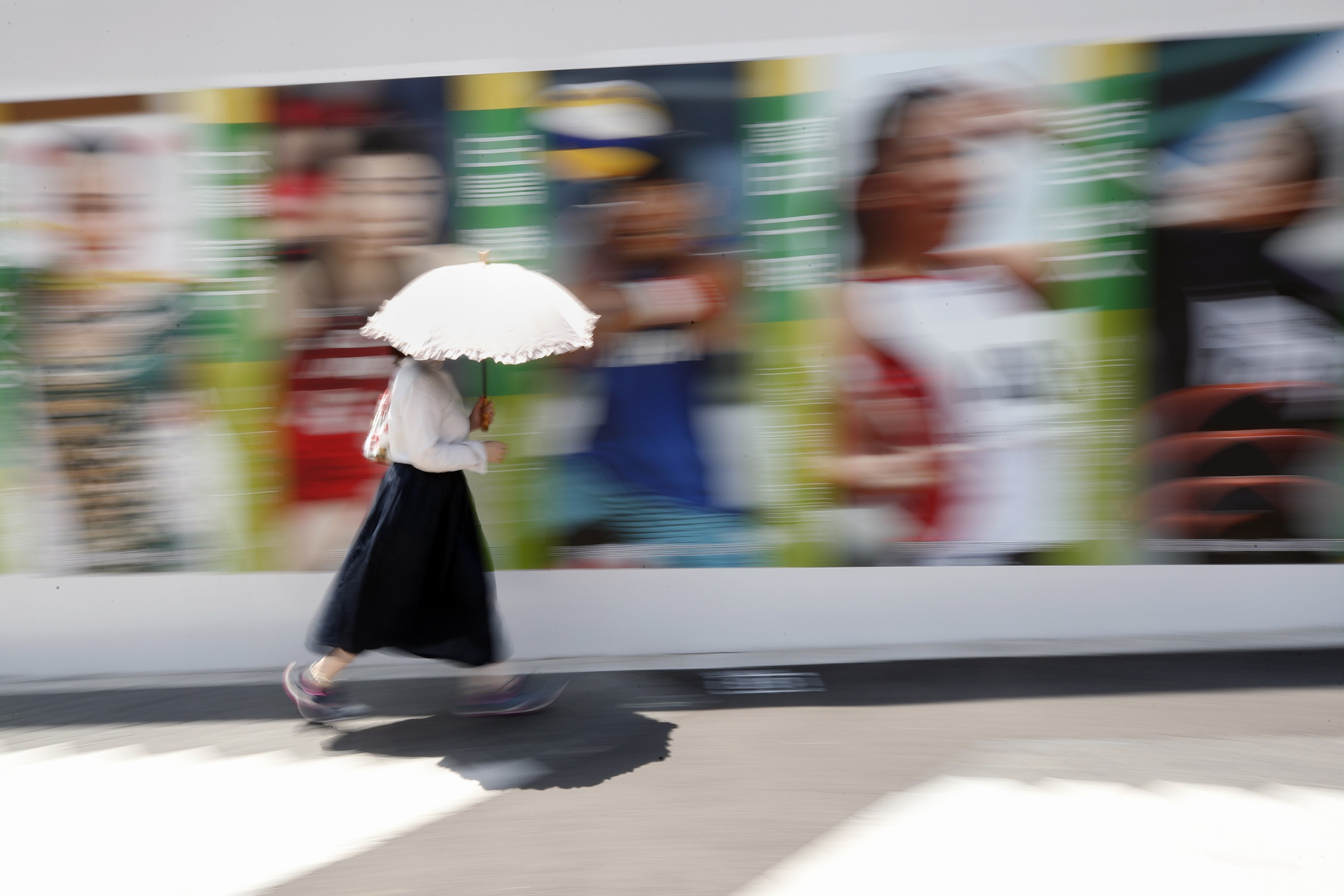 A pedestrian walks past a billboard featuring Japanese athletes to promote the Tokyo 2020 Olympics, in Tokyo on July 20. Photo: EPA-EFE