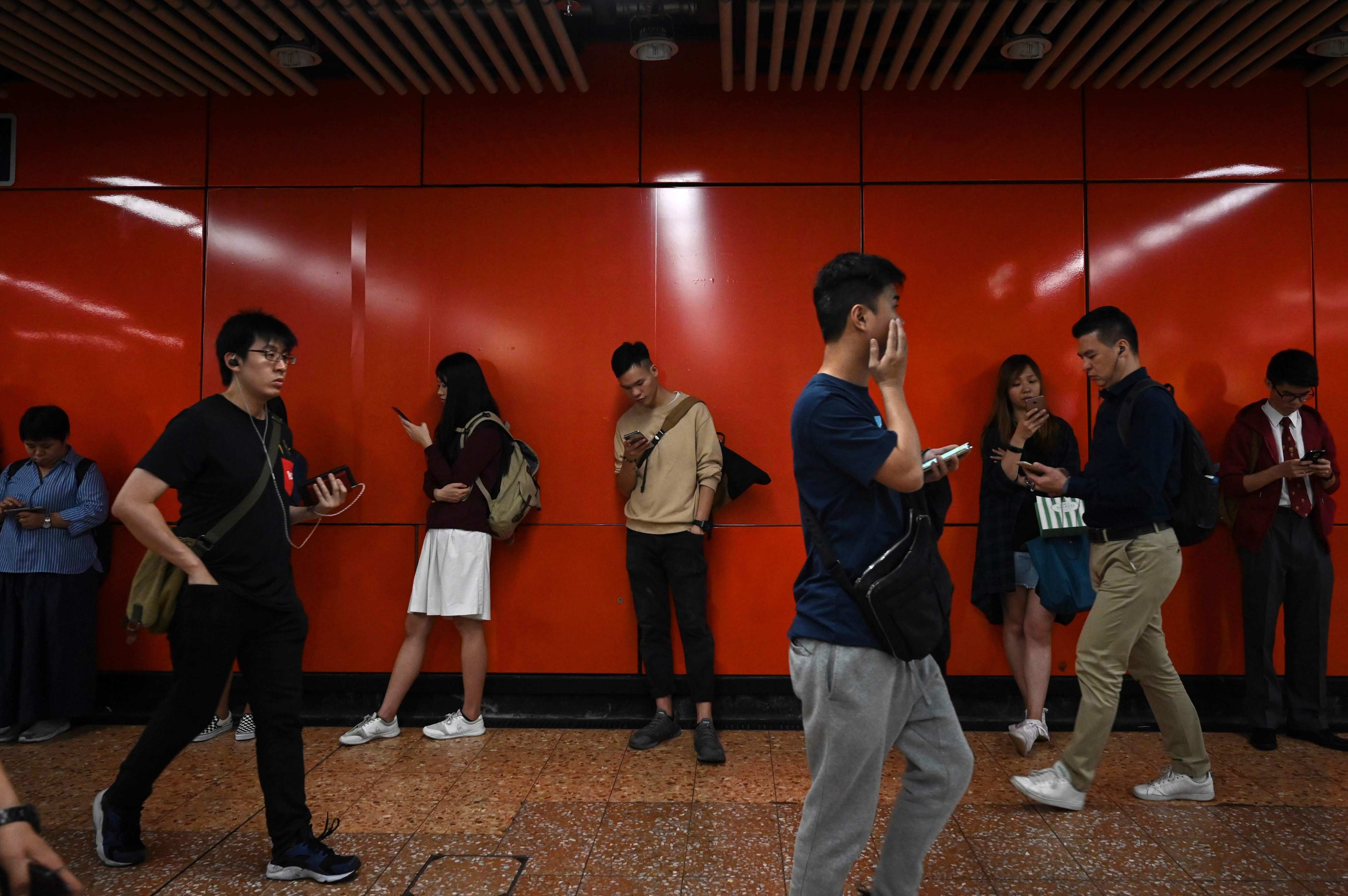Commuters use their mobile phones as they stand in an MTR train station in Hong Kong’s Kowloon district in December 2018. Emotive social feeds are good for advertising businesses, but destructive to mental health and social cohesion. Photo: AFP 