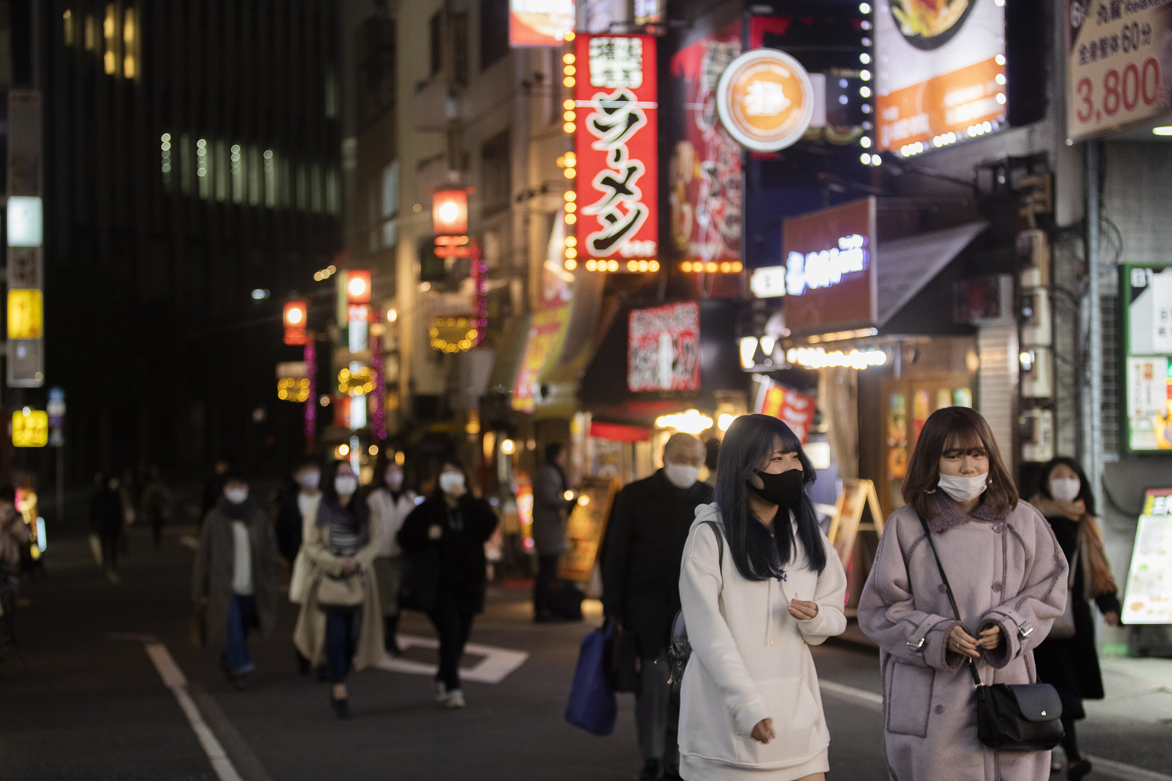 People wearing face masks walk on a street filled with restaurants and bars during a coronavirus state of emergency in Tokyo. Photo: AP