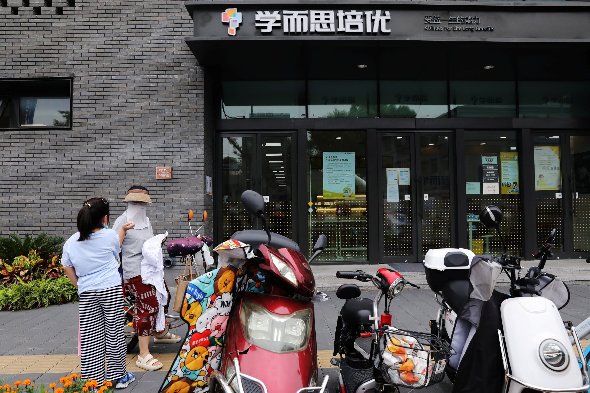 People stand outside a Xueersi outlet, a private educational services provider owned by TAL Education Group, in Beijing, on July 26. The share prices of TAL Education and New Oriental Education – two of the largest US-listed Chinese education companies – have plunged 72 per cent and 67 per cent respectively since July 23. Photo: Reuters