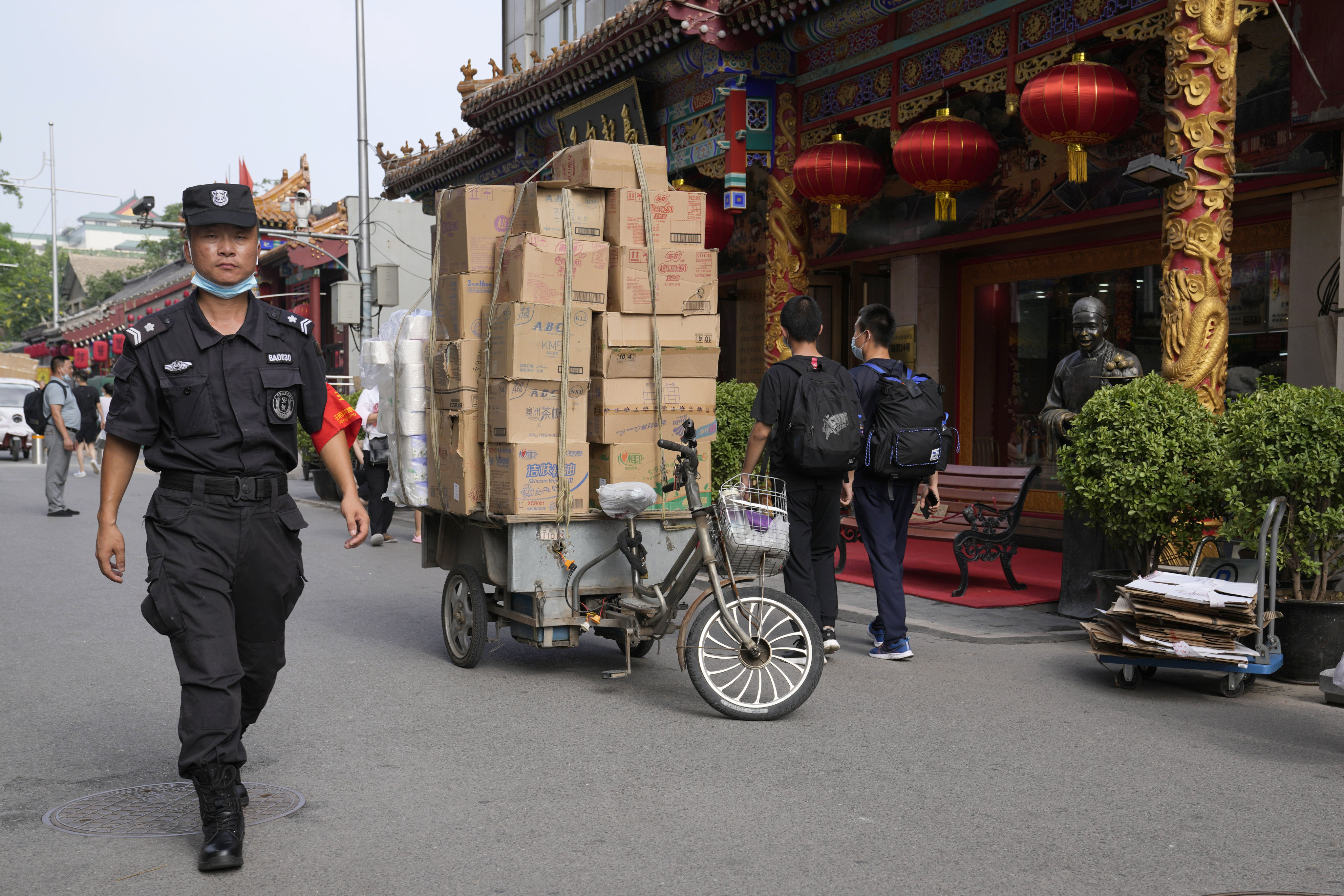 A security guard walks past deliveries on the Wangfujing retail street in Beijing on July 14. China’s economic data for July illustrates a broad-based slowing in economic activity. Photo: AP  