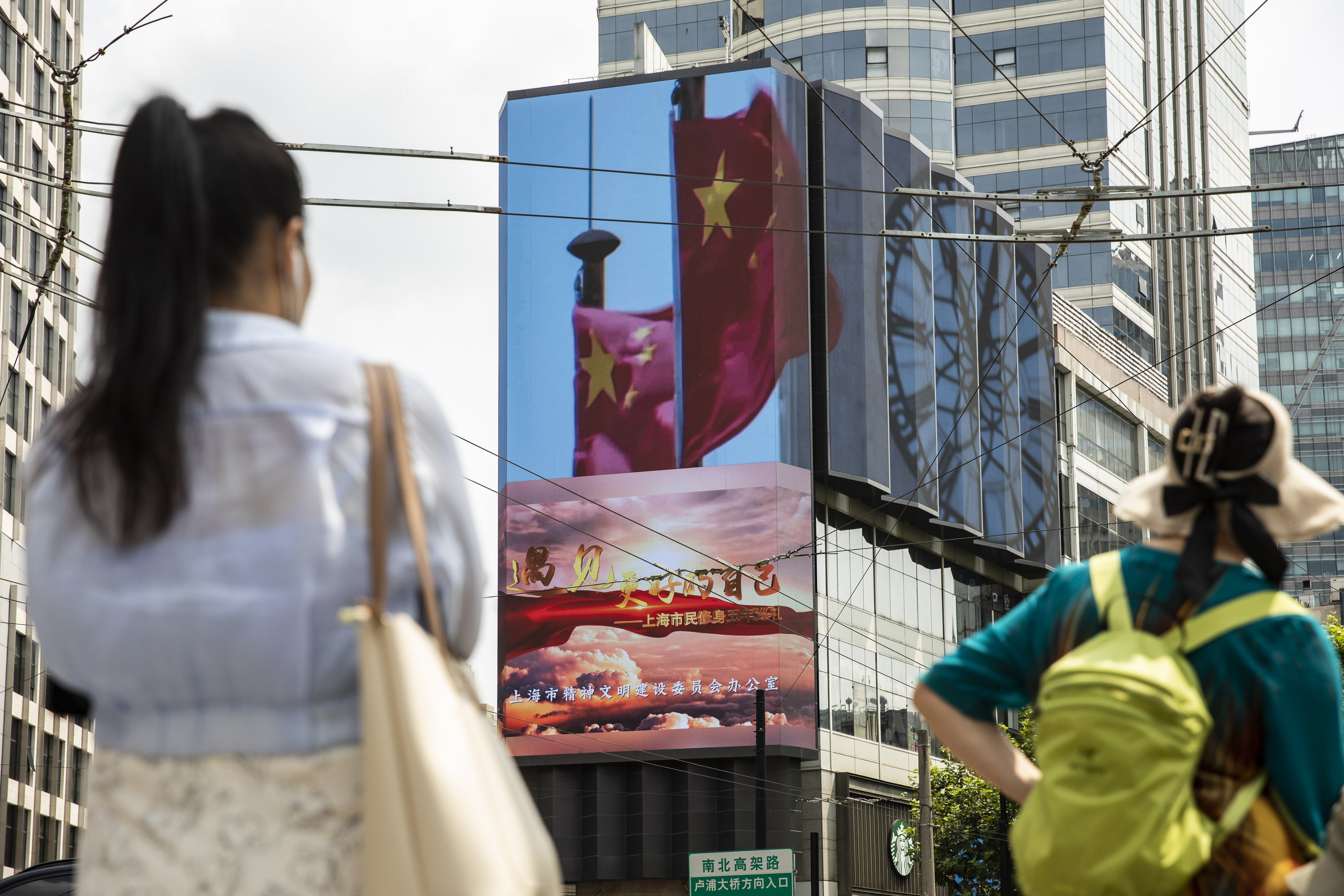 An advertising screen displays an image of Chinese flags in Shanghai on August 18. President Xi Jinping said China must pursue ‘common prosperity’, in which wealth is shared by all people, as a key feature of a modern economy while also curbing financial risks. Photo: Bloomberg