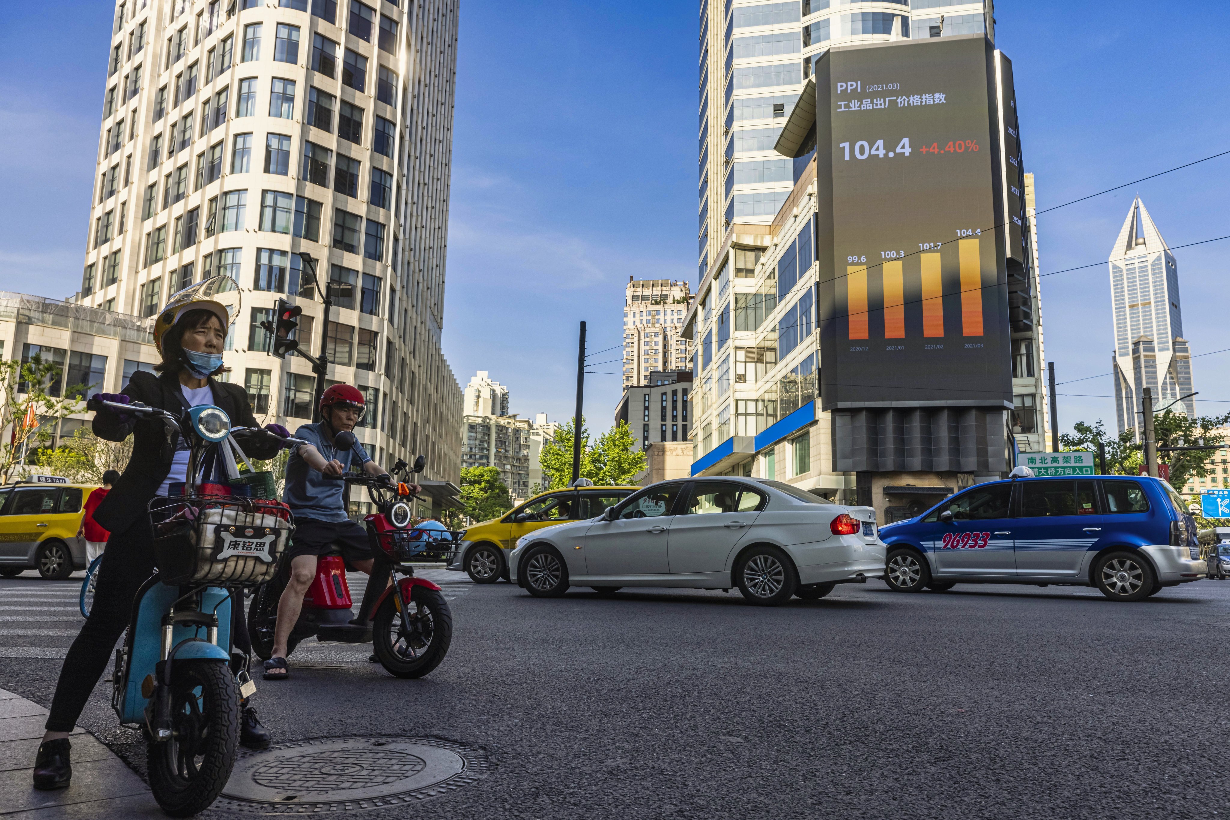Motorists pass under a large screen showing stock market data in Shanghai on May 10. Photo: EPA-EFE 