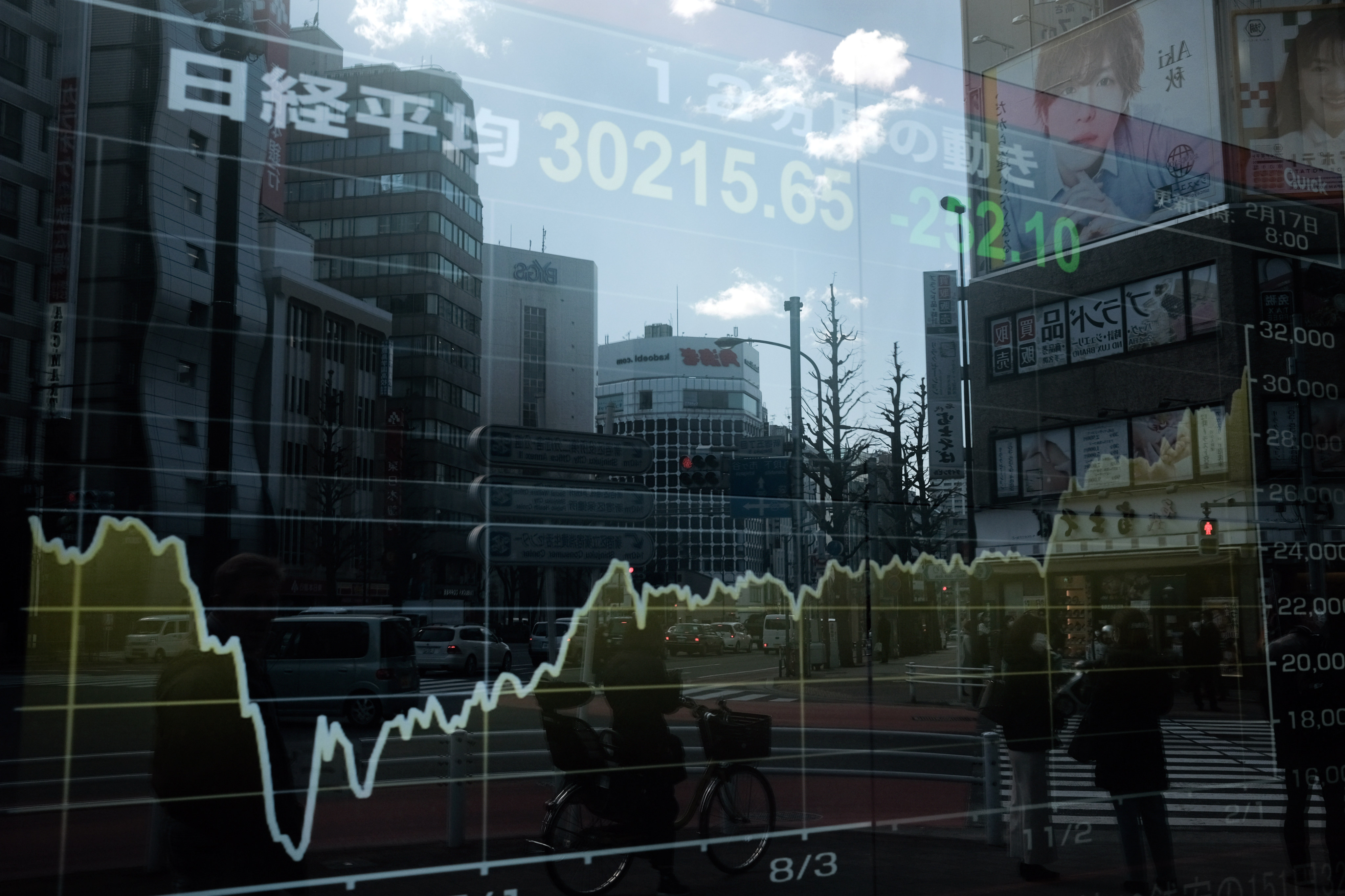Buildings and pedestrians are reflected on an electronic stock board outside a securities firm in the Shinjuku district of Tokyo, Japan, on February 17. Photo: Bloomberg