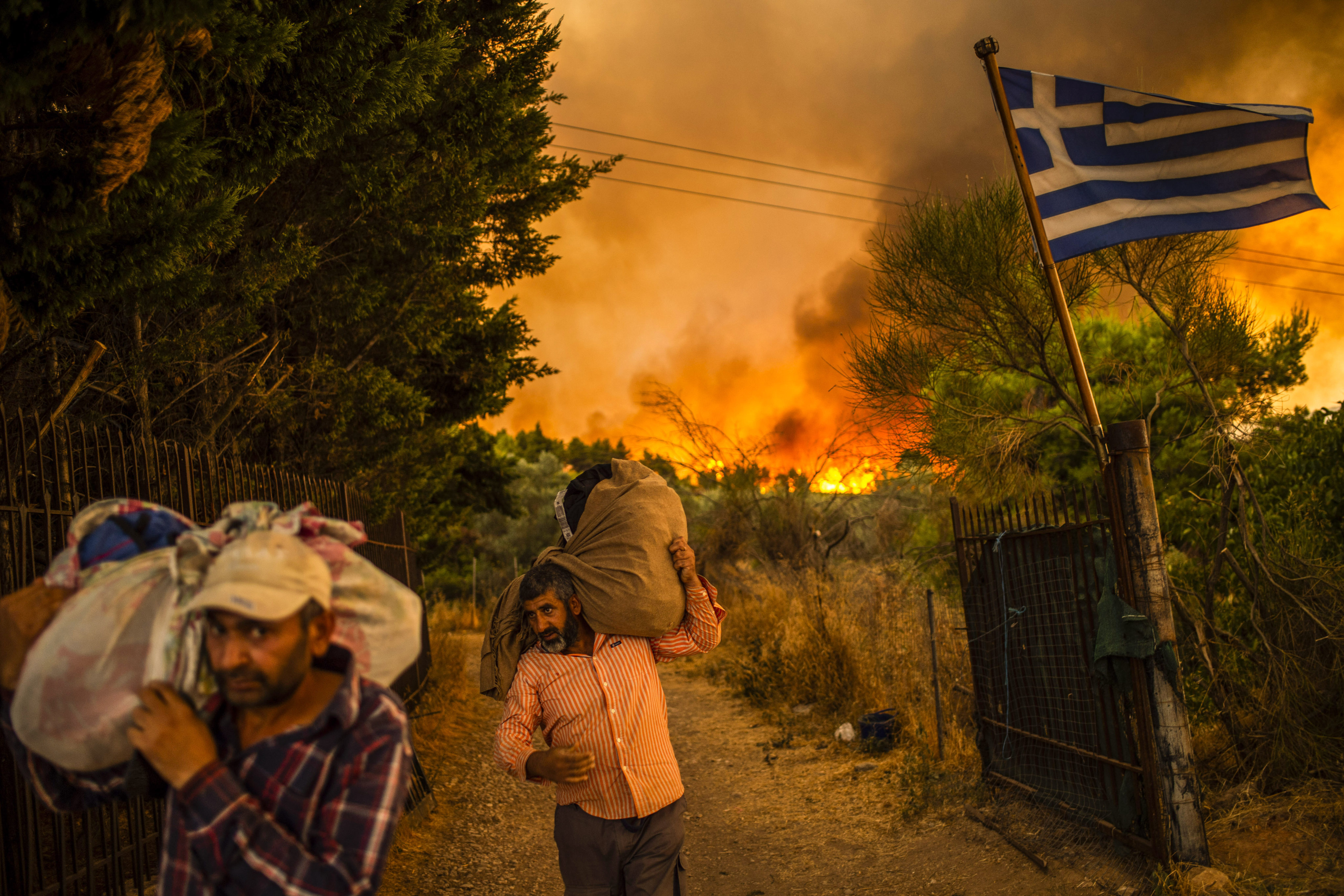 People move their belongings to safety as a wildfire rages in a wooded area north of Athens on August 6. Photo: DPA