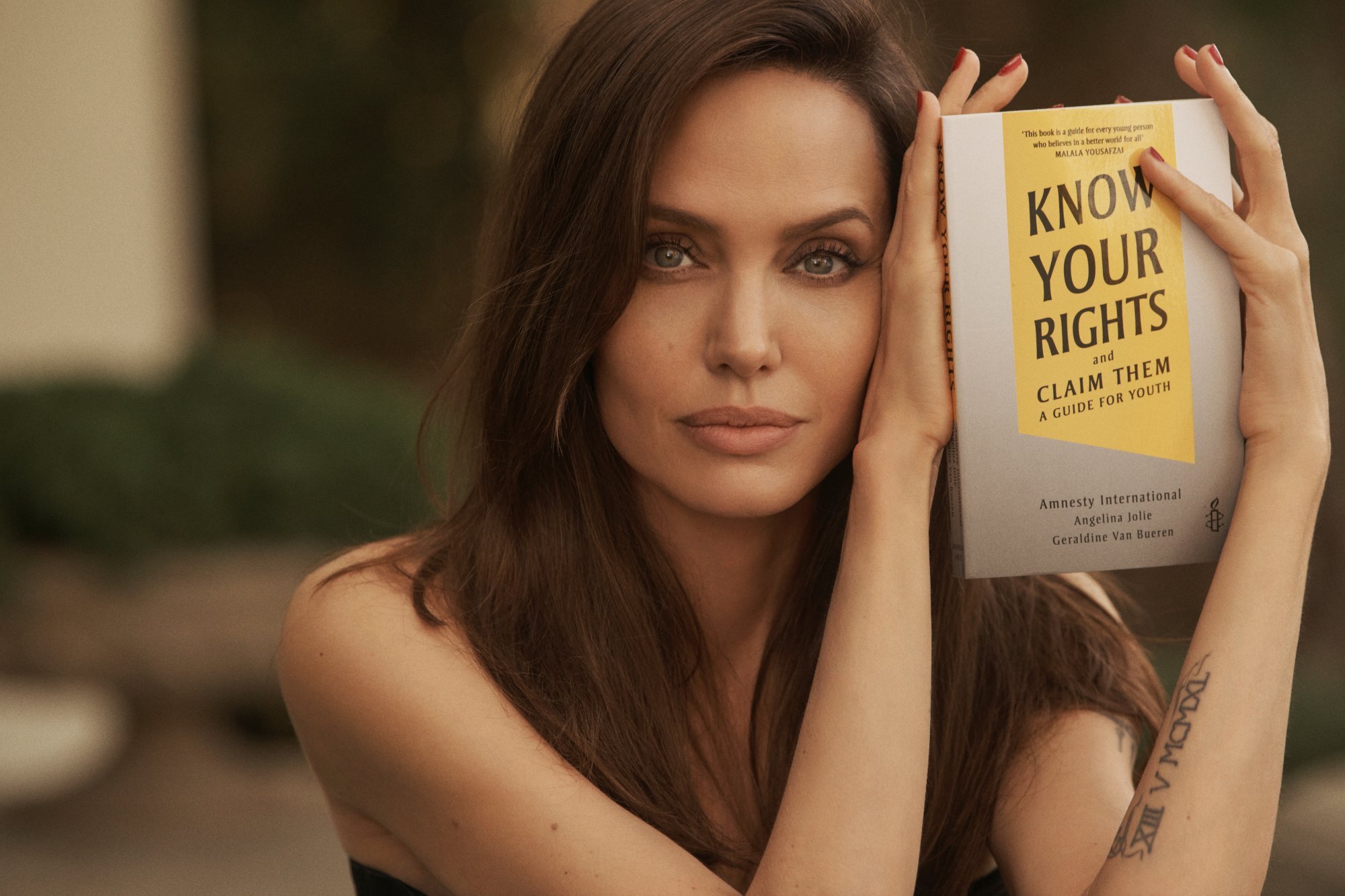 Actor Angelina Jolie poses with the book Know Your Rights (And Claim Them). Photo: Amnesty International/Handout via Reuters