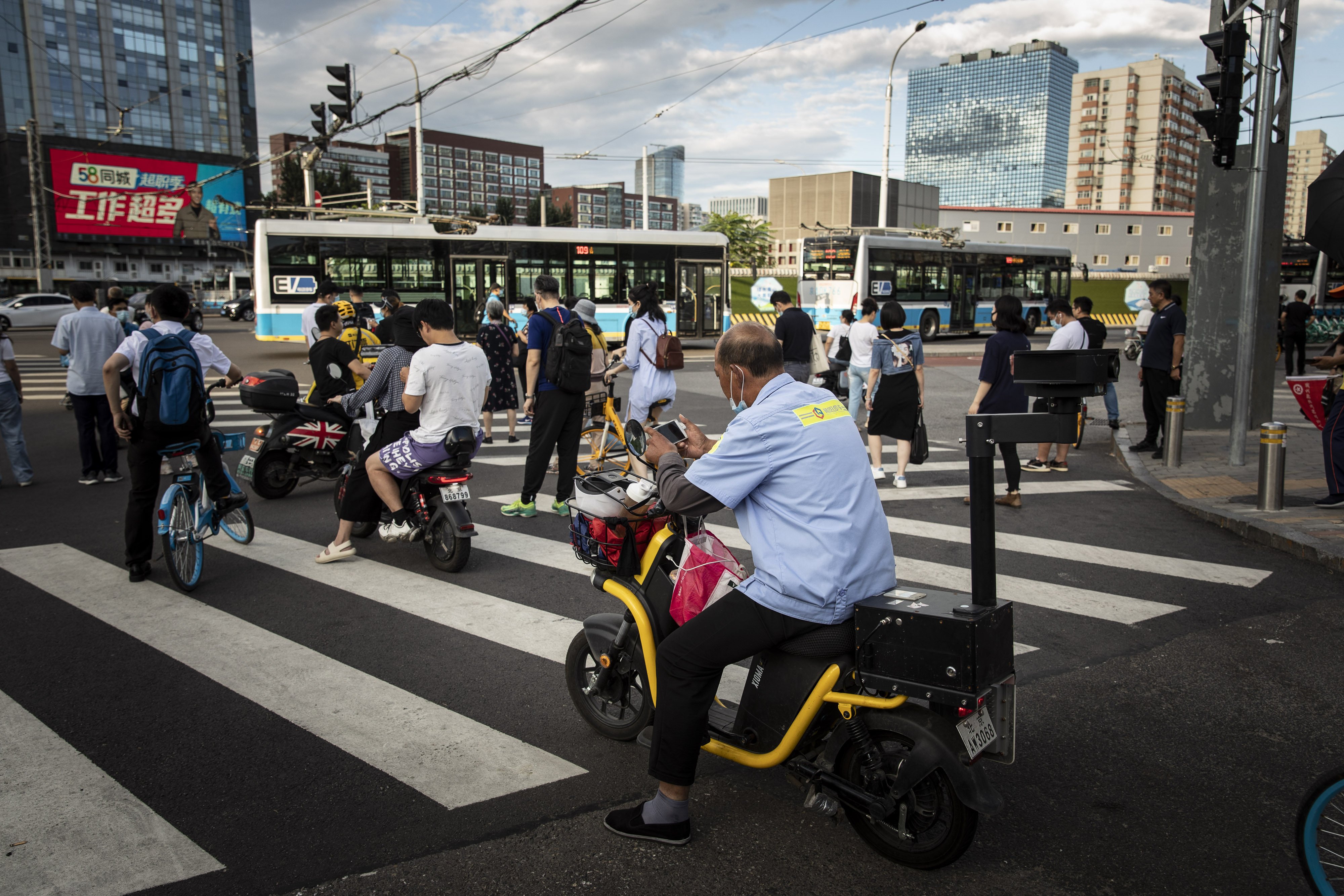 Commuters wait at a traffic intersection in Beijing on August 25. China has vowed to promote the welfare of all people and redistribute income, underscoring its push to achieve “common prosperity” in the country. Photo: Bloomberg