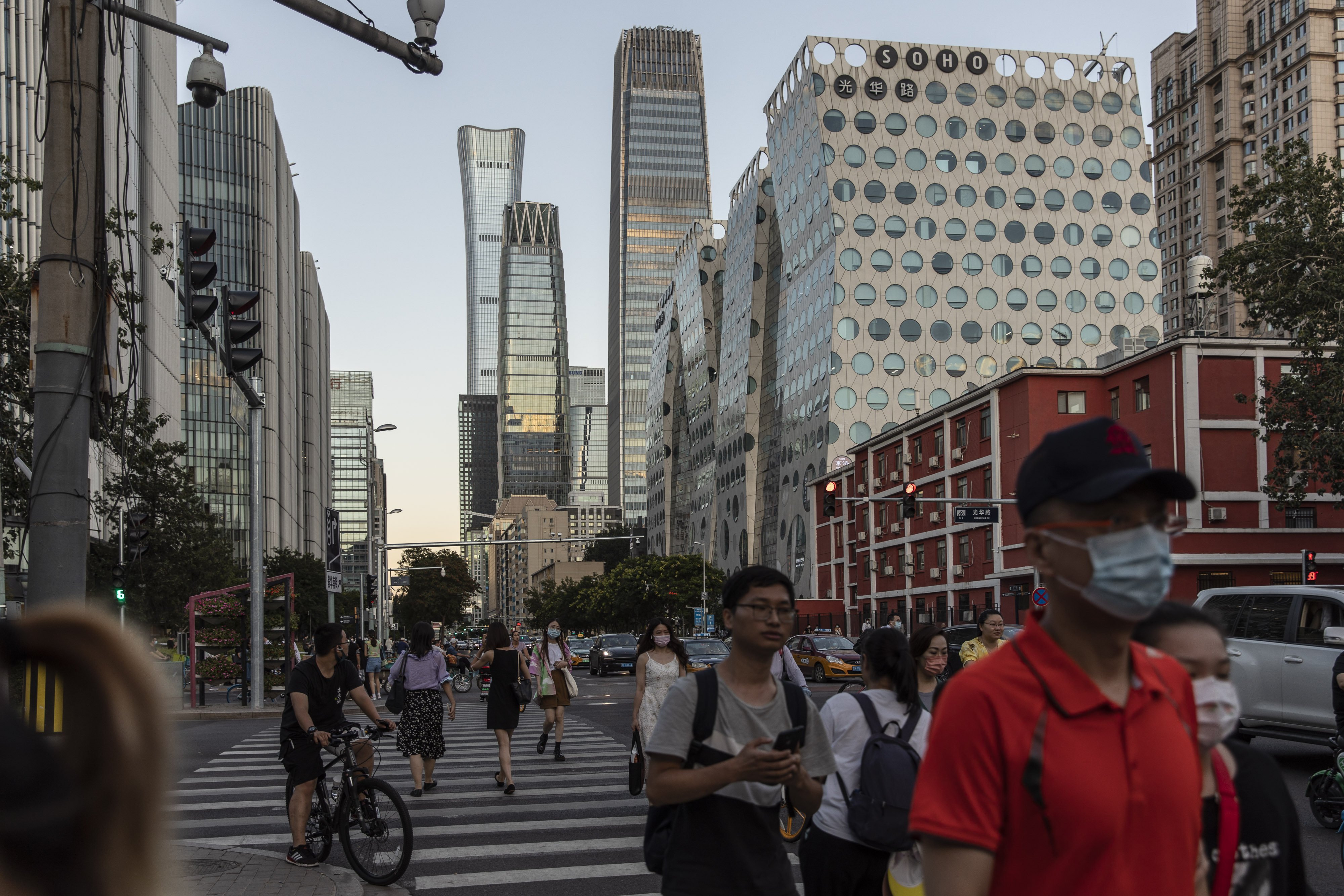 Pedestrians cross a traffic intersection near commercial buildings in Beijing, on August 25. The impact of common prosperity on foreign-owned multinational corporations will range from basic and universal to sophisticated and specific. Photo: Bloomberg
