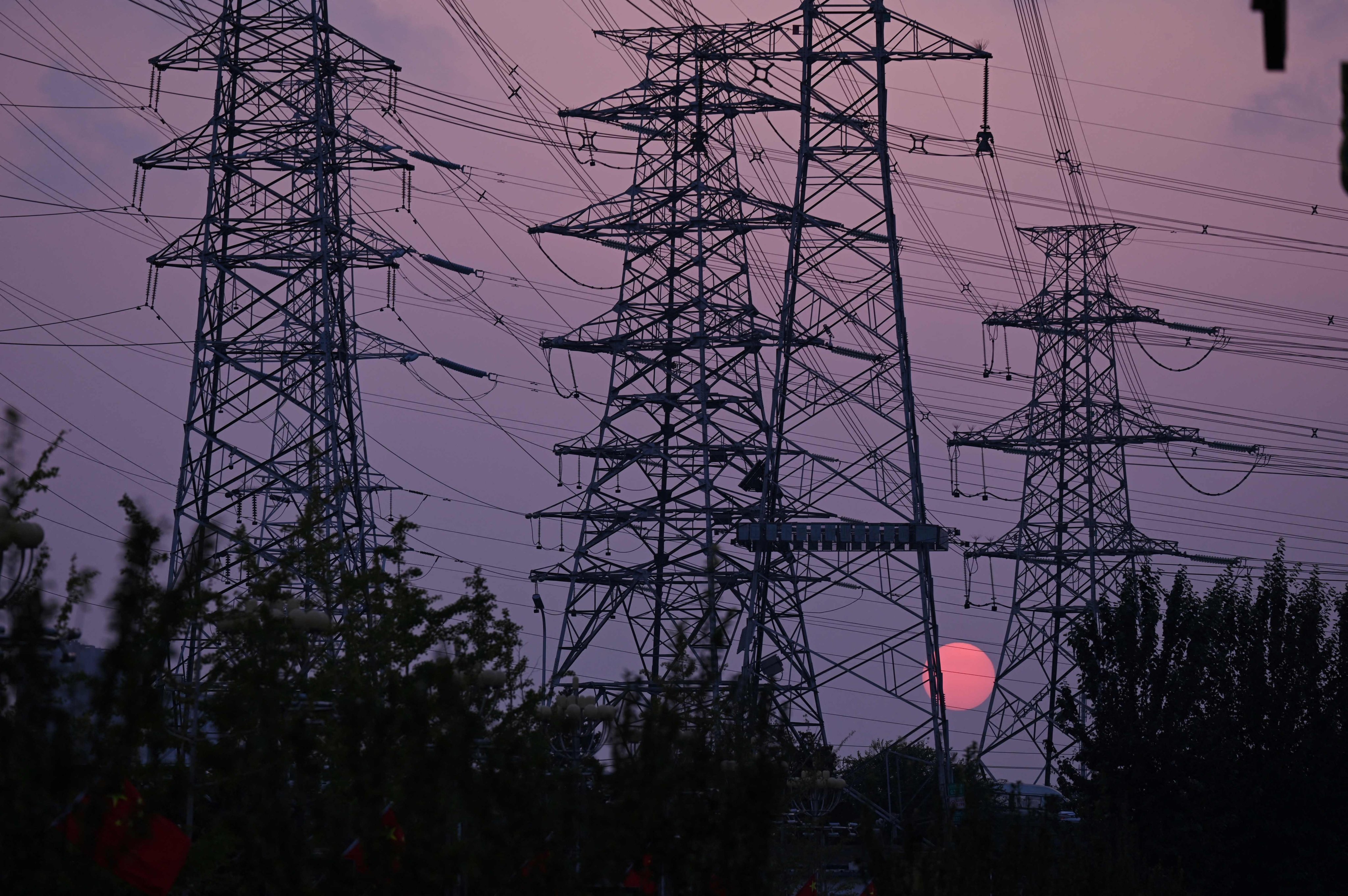 The sun sets behind electricity pylons in Beijing on September 28. Coronavirus outbreaks, a cooling housing market and spreading power shortages have been weighing on the Chinese economy. Photo: AFP 