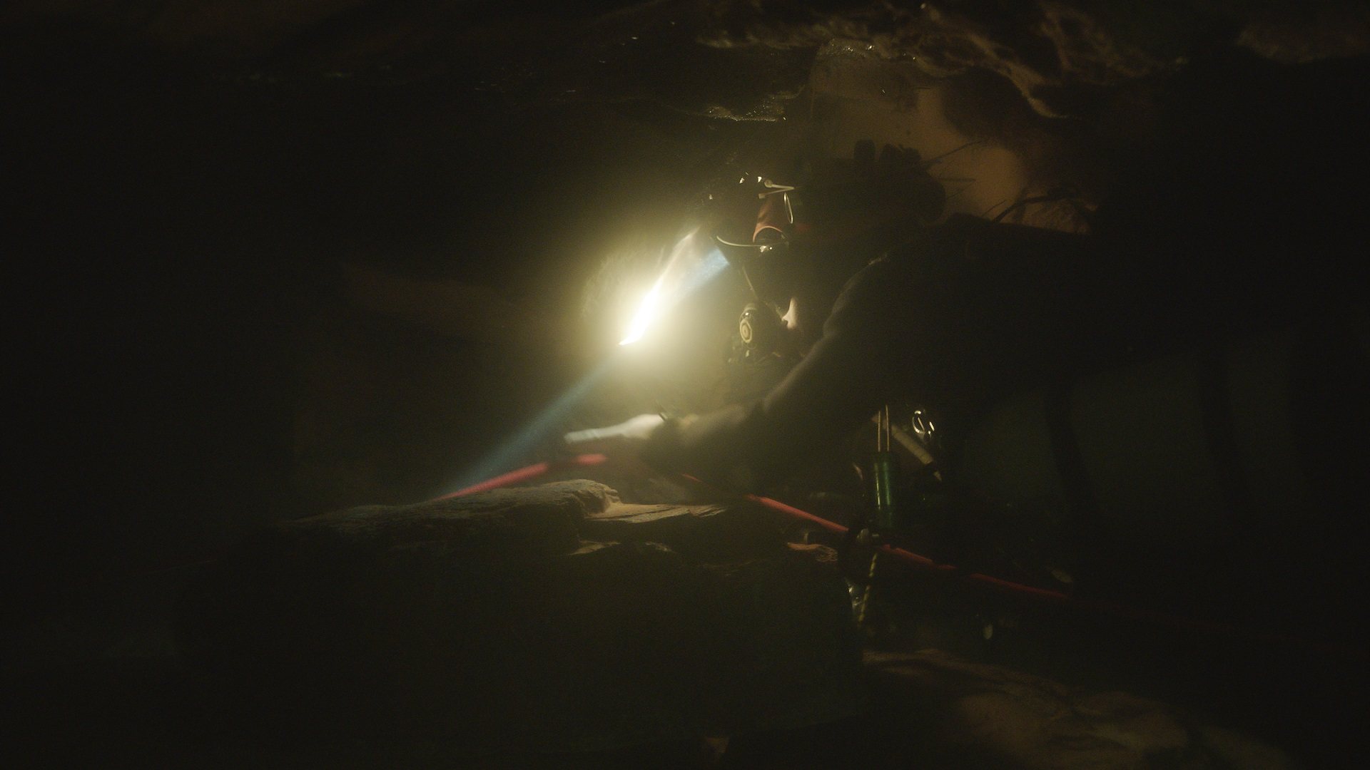 A diver swims through a dark cave guided by a headlamp.  THE RESCUE chronicles the 2018 rescue of 12 Thai boys and their soccer coach, trapped deep inside a flooded cave. E. Chai Vasarhelyi and Jimmy Chin reveal the perilous world of cave diving, bravery of the rescuers, and dedication of a community that made great sacrifices to save these young boys. Photo: National Geographic.
