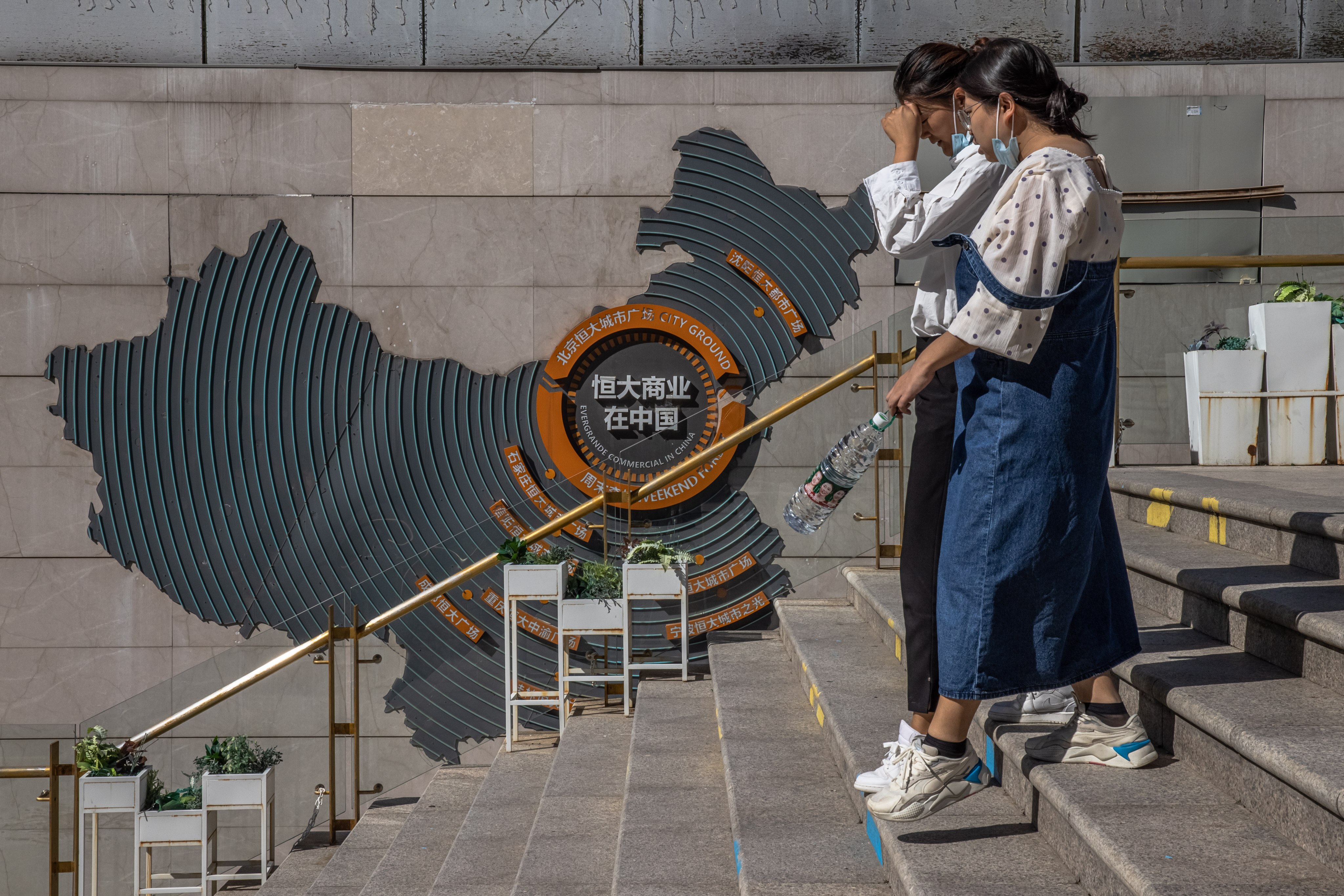 Women in Beijing walk past a map showing Evergrande’s commercial hubs in China, on September 22. Evergrande may have fallen from grace, but China’s scale bias will persist. Photo: EPA-EFE