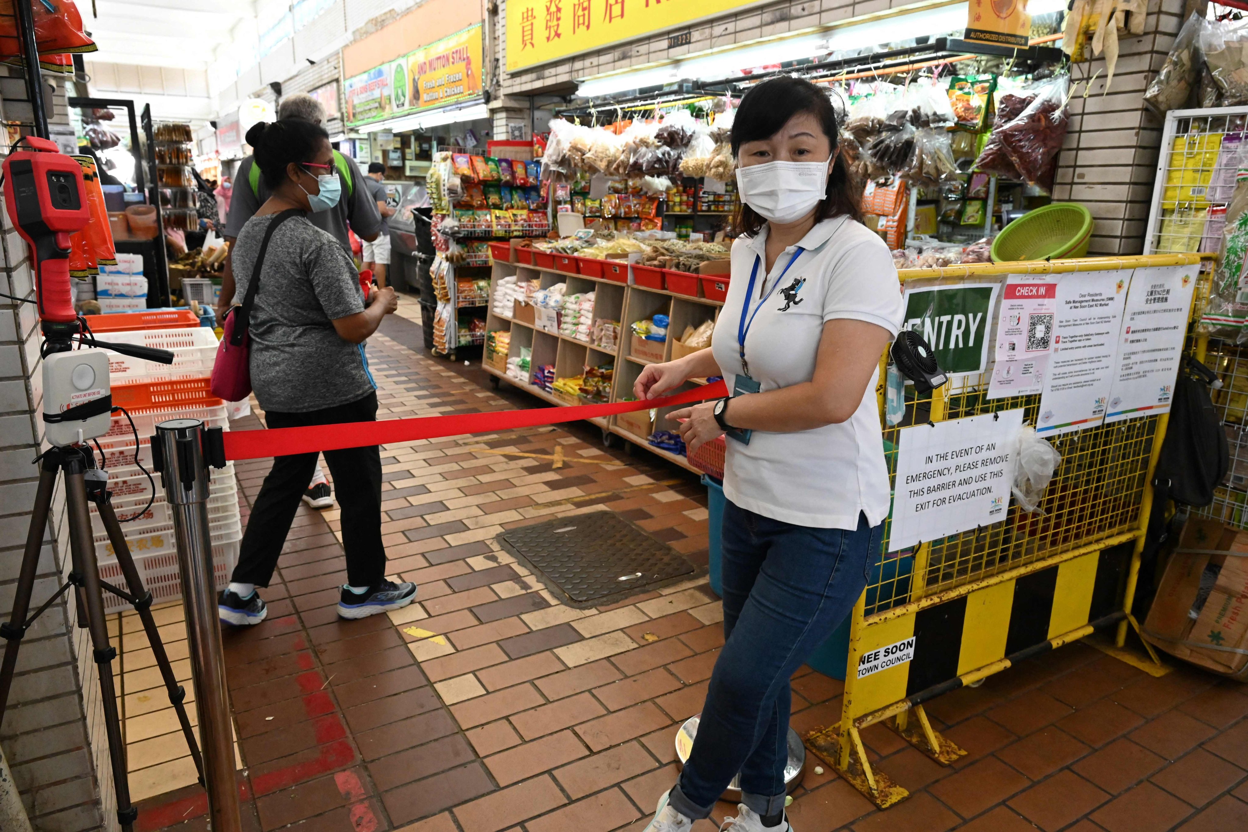 A health official stands guard at the entrance of a market in Singapore on October 9 to manage the flow of people in an attempt to curb the spread of Covid-19. Photo: AFP