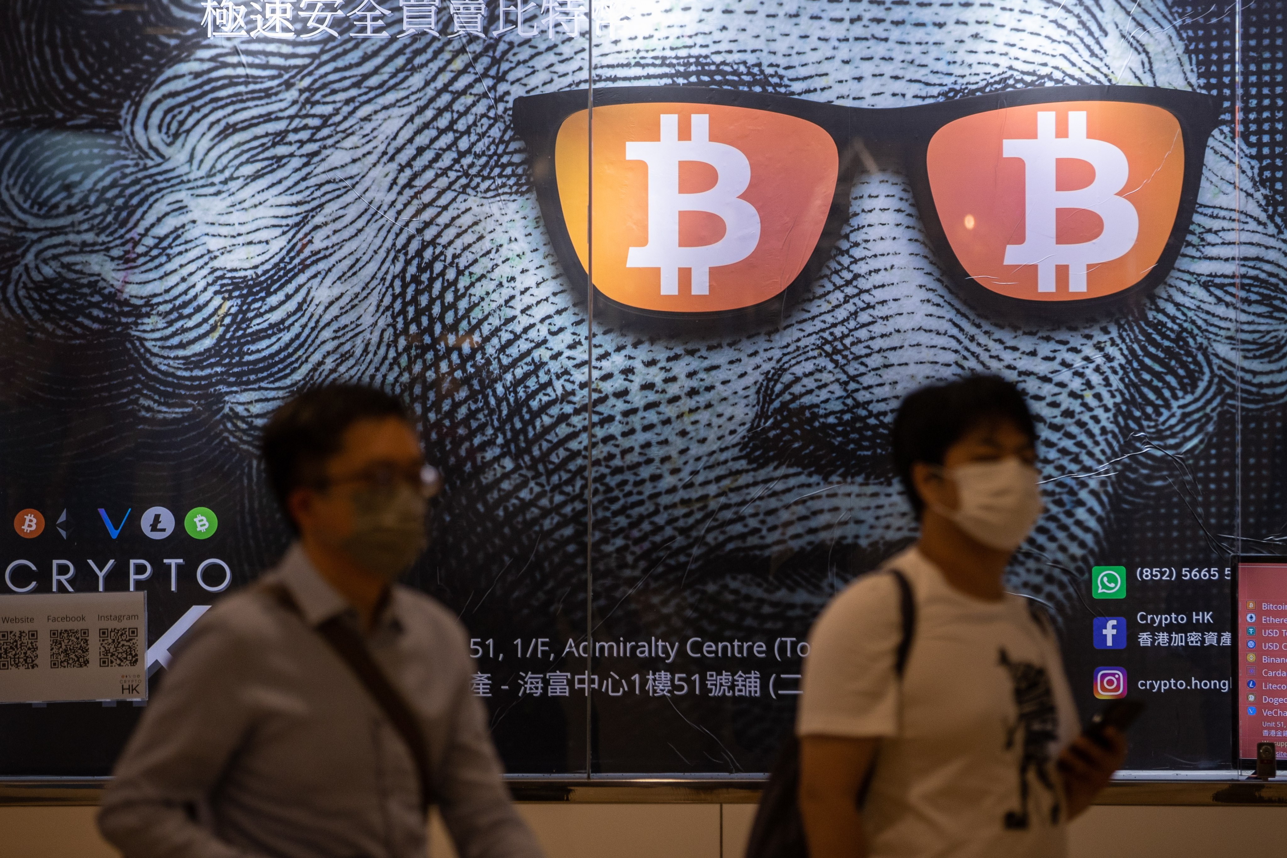 Two men walk past a poster for bitcoin and other cryptocurrencies in Hong Kong on September 25. Photo: EPA-EFE