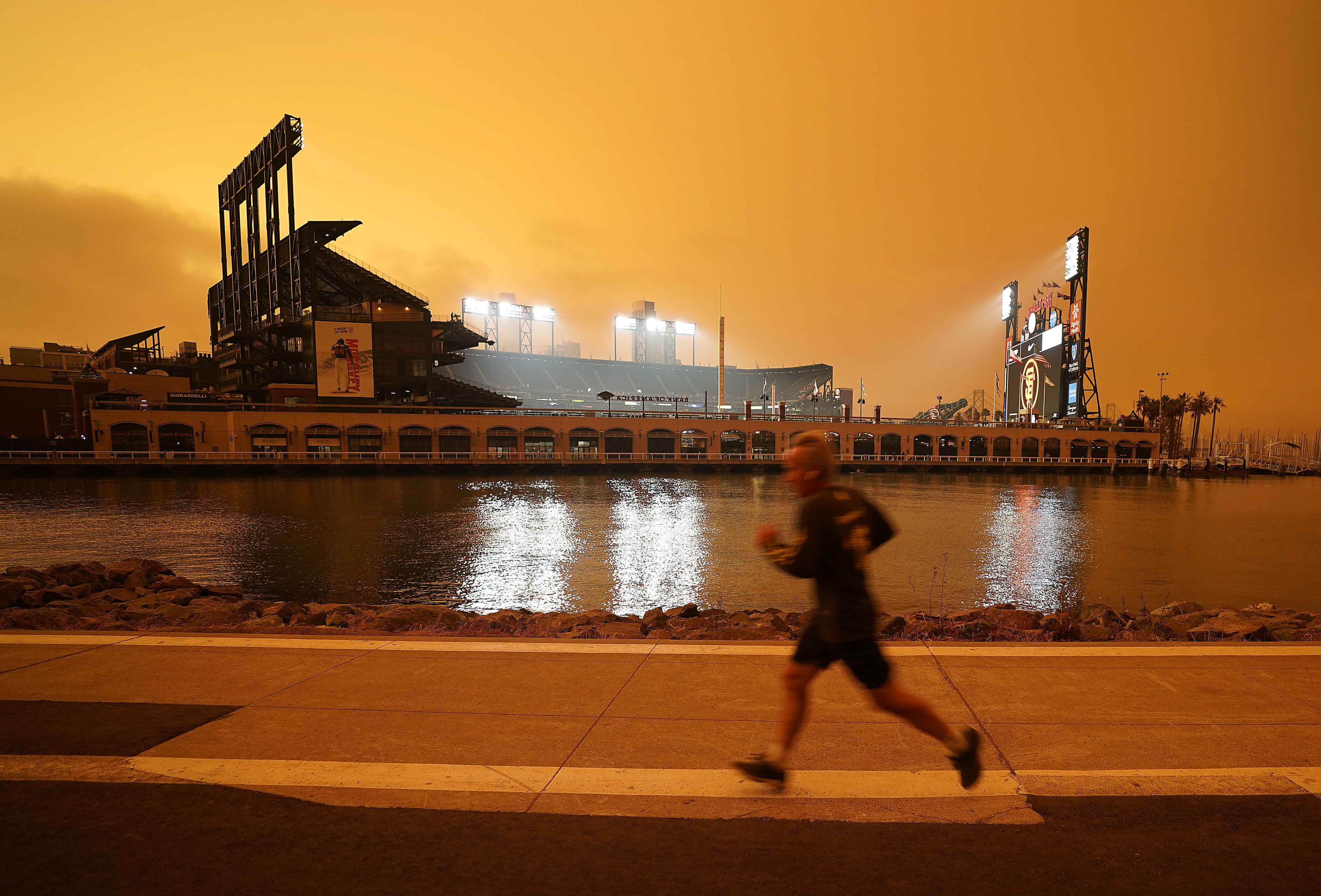 A jogger runs along McCovey Cove outside Oracle Park in San Francisco, under skies reddened from wildfire smoke, on September 9, 2020. Photo: AP