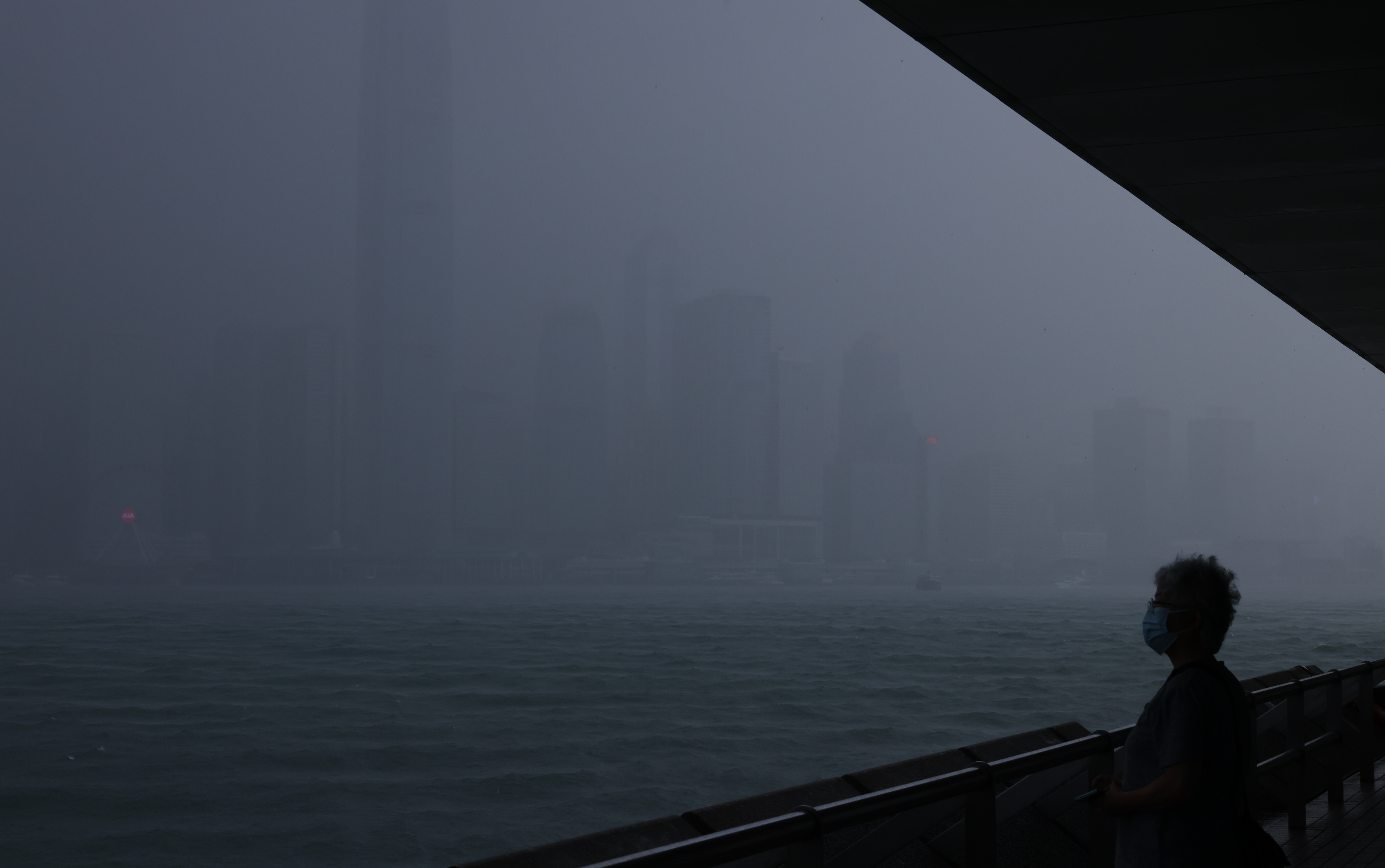 A woman looks out across Victoria Harbour as the Hong Kong Observatory issues the first typhoon warning No 1 signal in 2021 on June 11. In October, Hong Kong issued two No 8 storm warning signals in four days. Photo: Dickson Lee